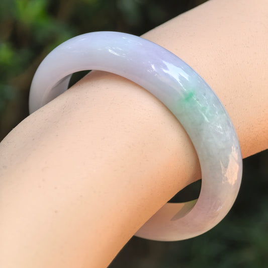 Natural Grade-A glutinous purple green oval jadeite bangle worn on the wrist.
