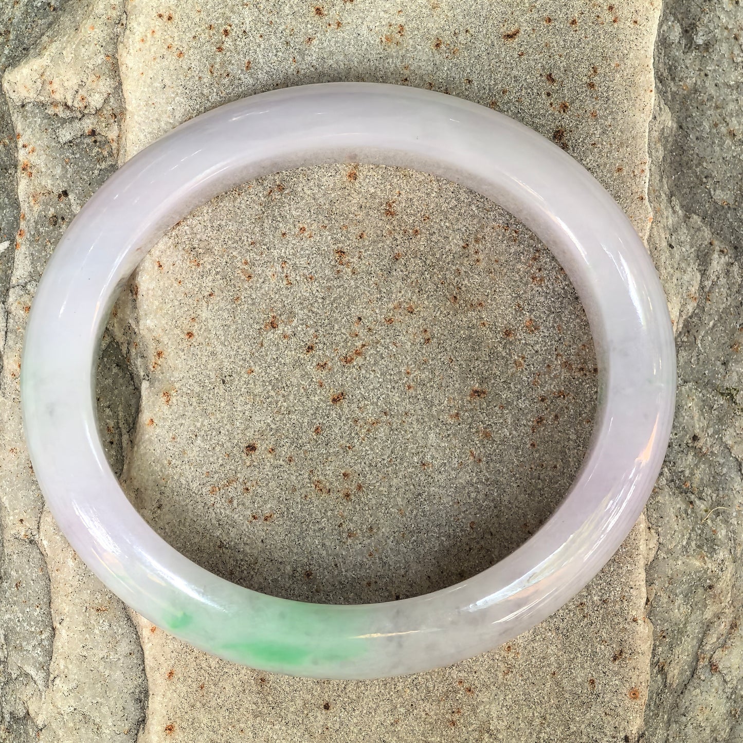 Top view of a lavender green oval jadeite bangle showing soft two-color tone.
