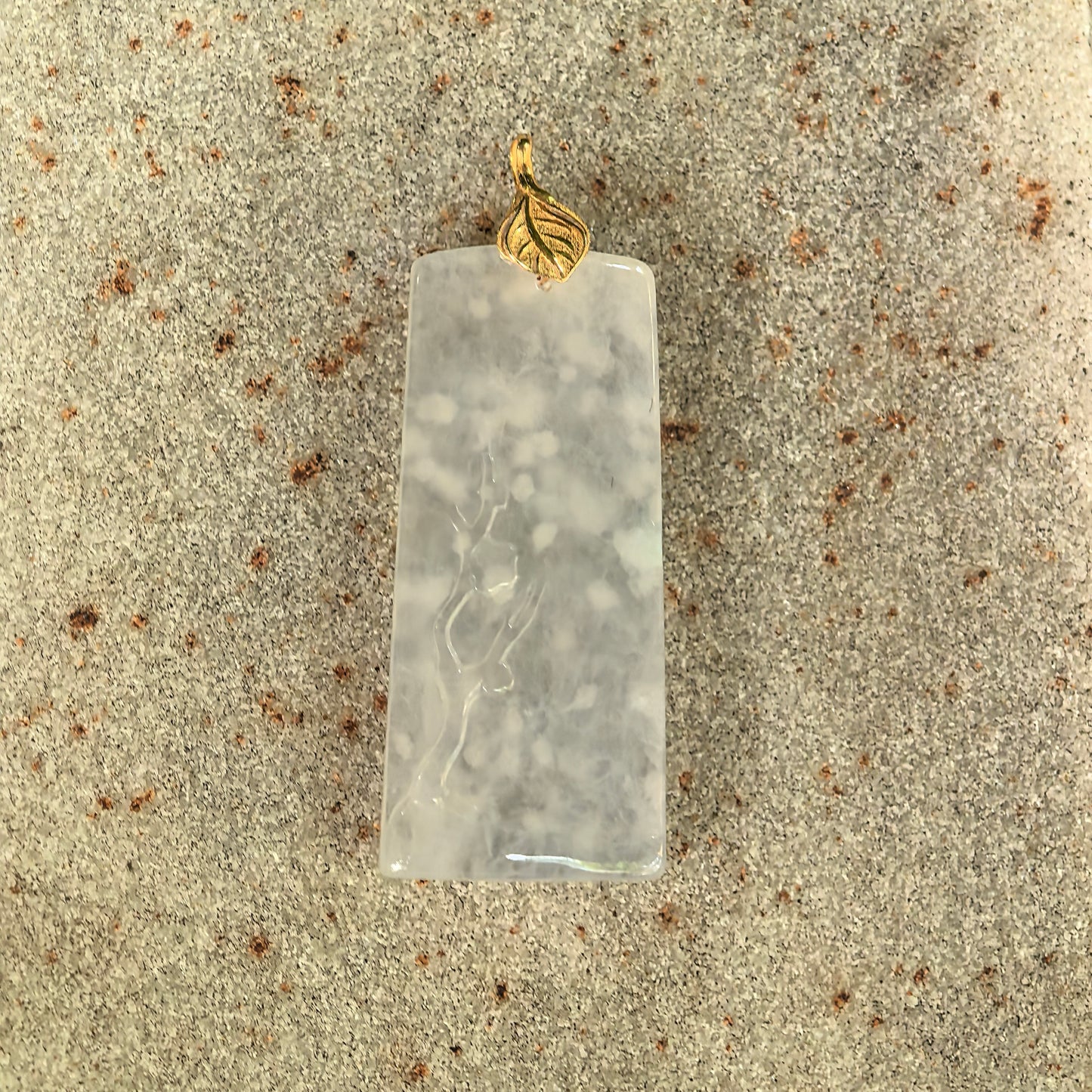 Rectangular jadeite pendant with carved plum blossom motif and smooth polished surface.
