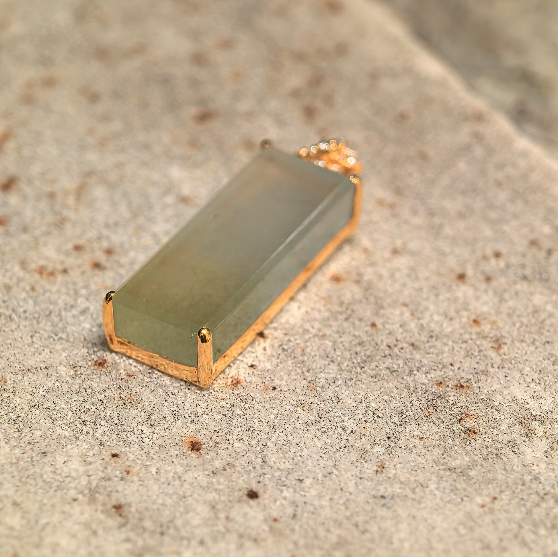 Angled view of an icy yellow jadeite pendant showing good translucency and gold setting.
