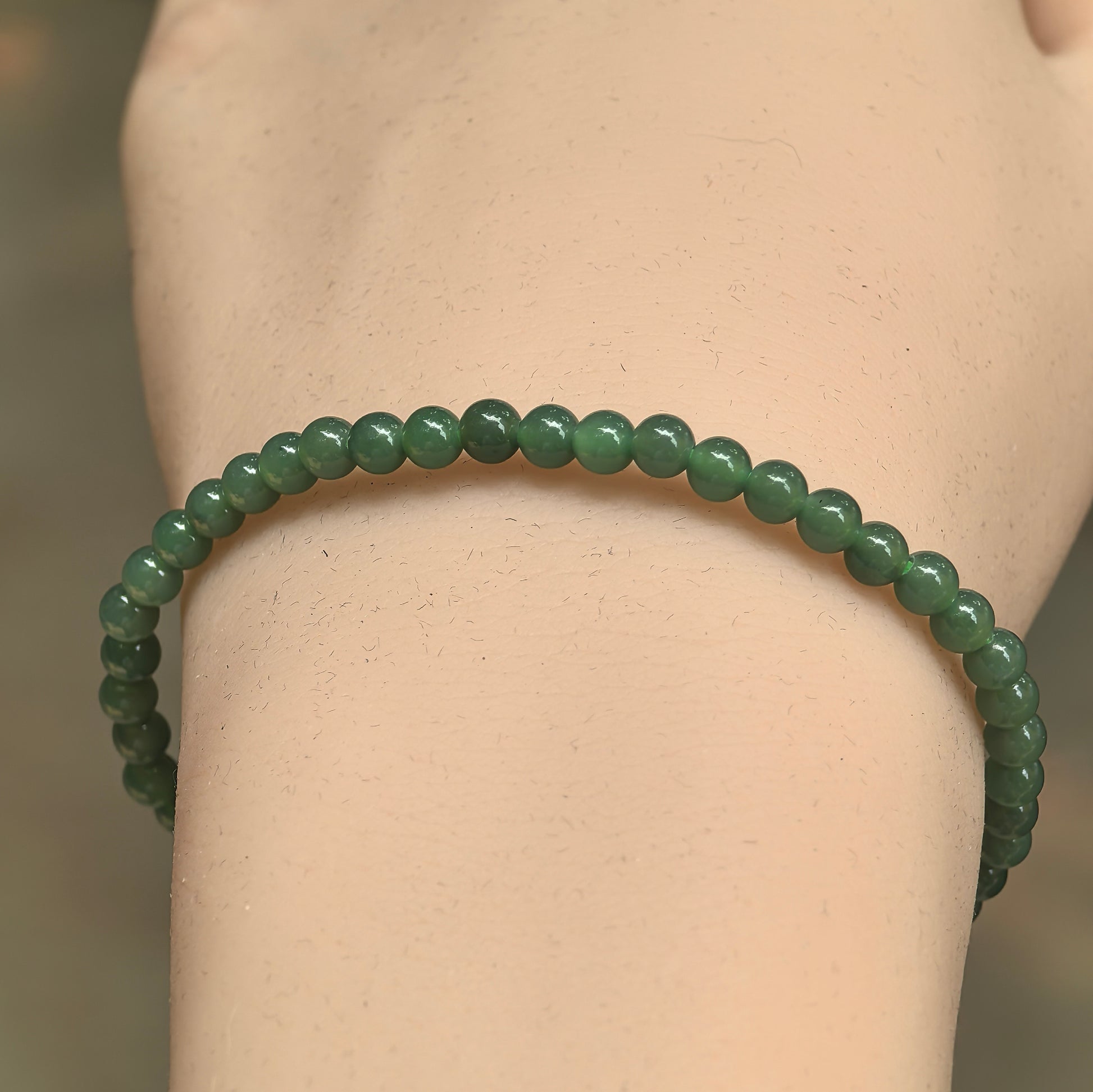 Close-up of slim green jadeite beads showing smooth luster and natural variation.

