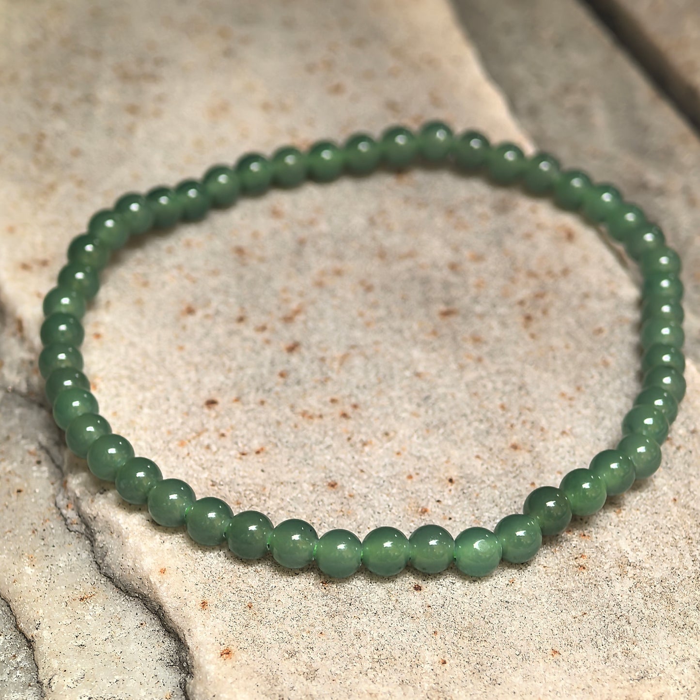 Detailed view of small round green jadeite bracelet beads with polished finish.