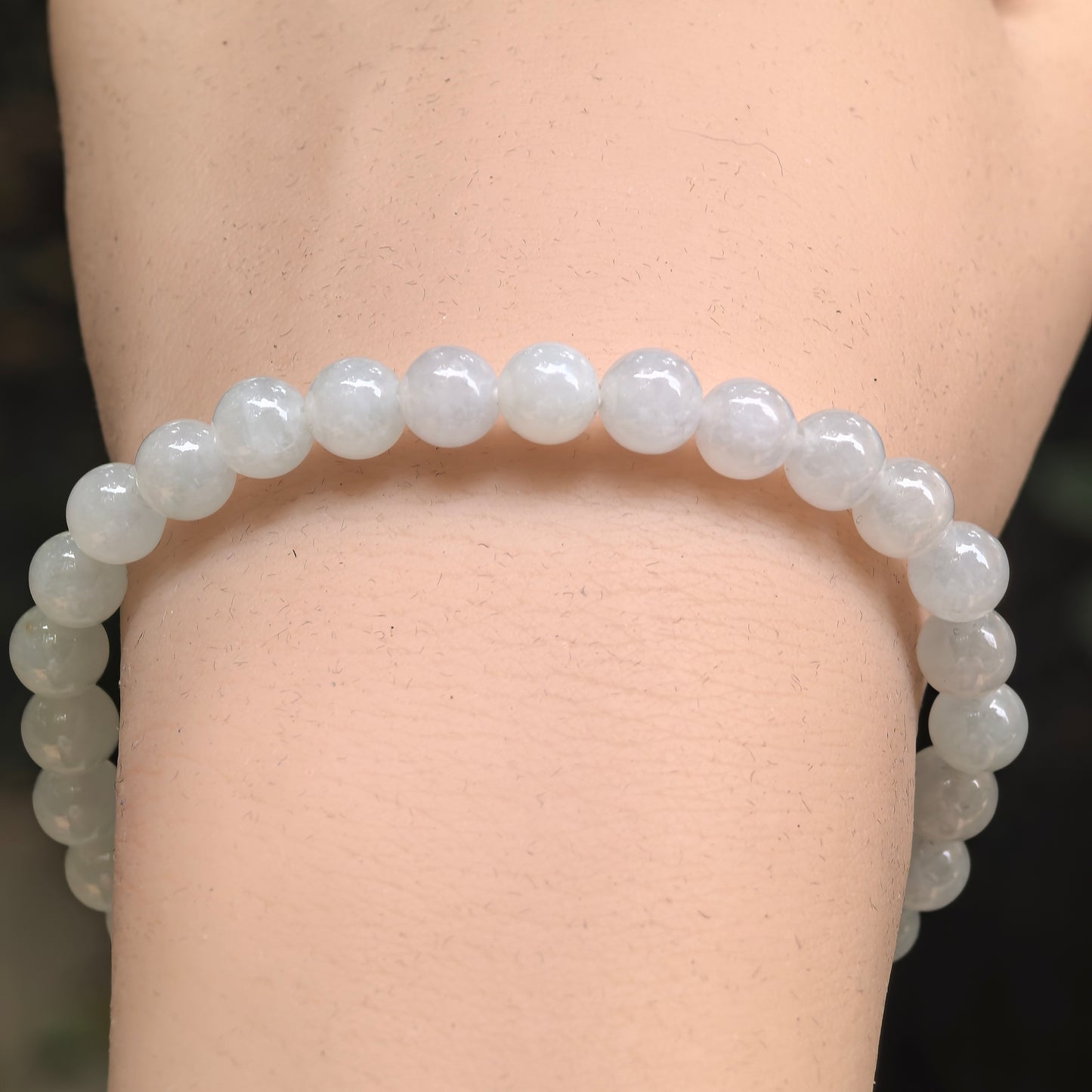 Close-up of white jadeite bracelet showing round beads and soft translucency.
