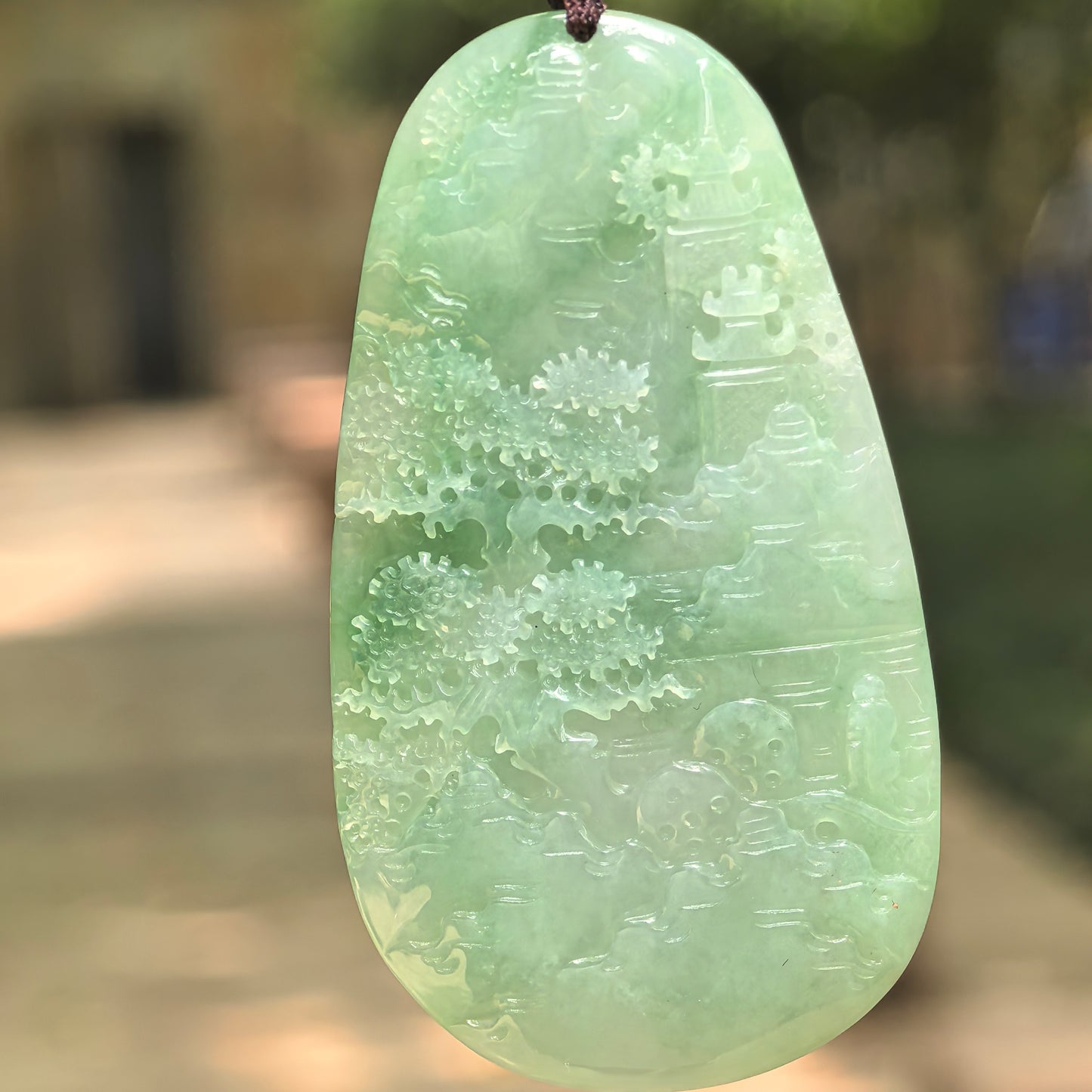 Natural Grade-A glutinous bright green landscape jadeite pendant in natural light.
