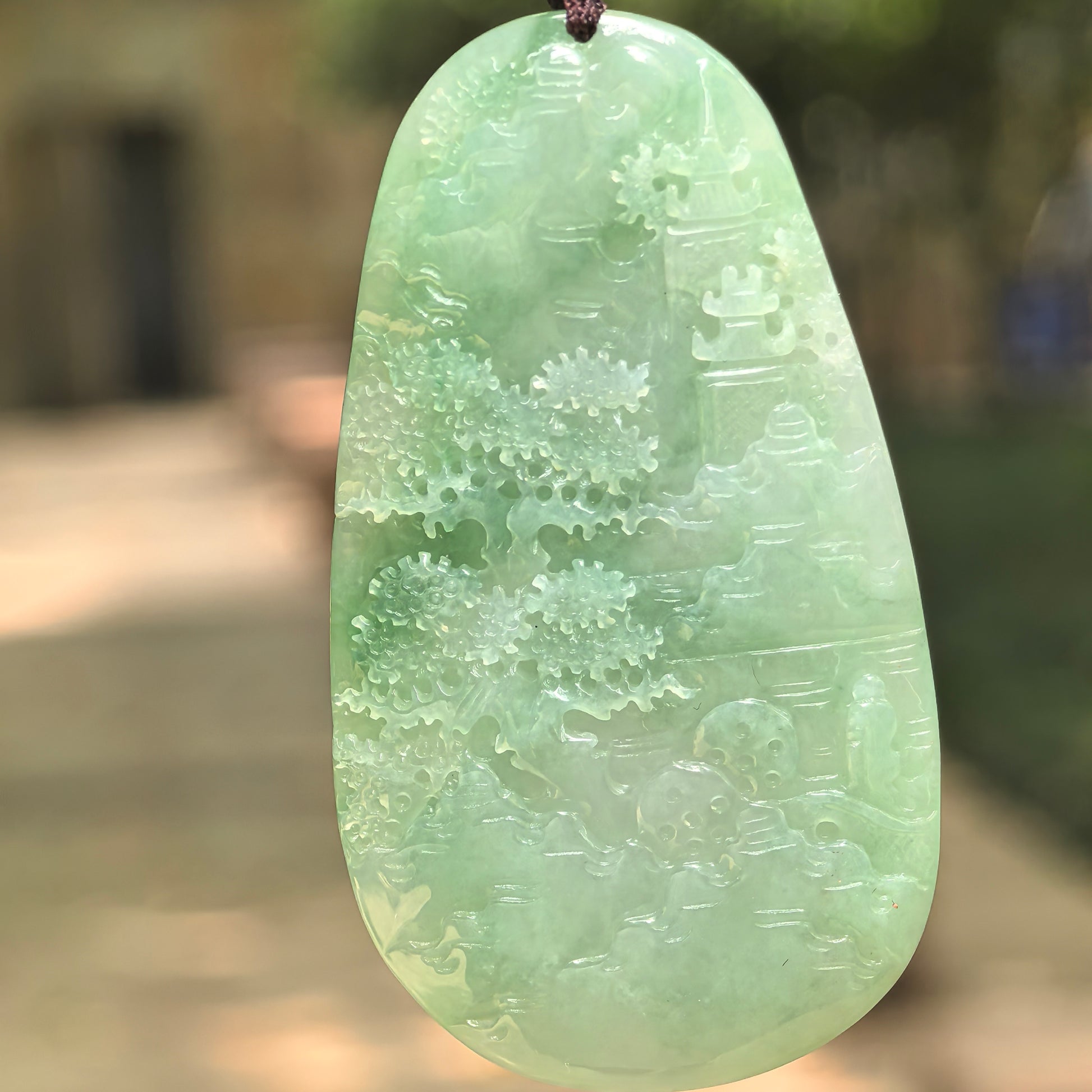 Natural Grade-A glutinous bright green landscape jadeite pendant in natural light.
