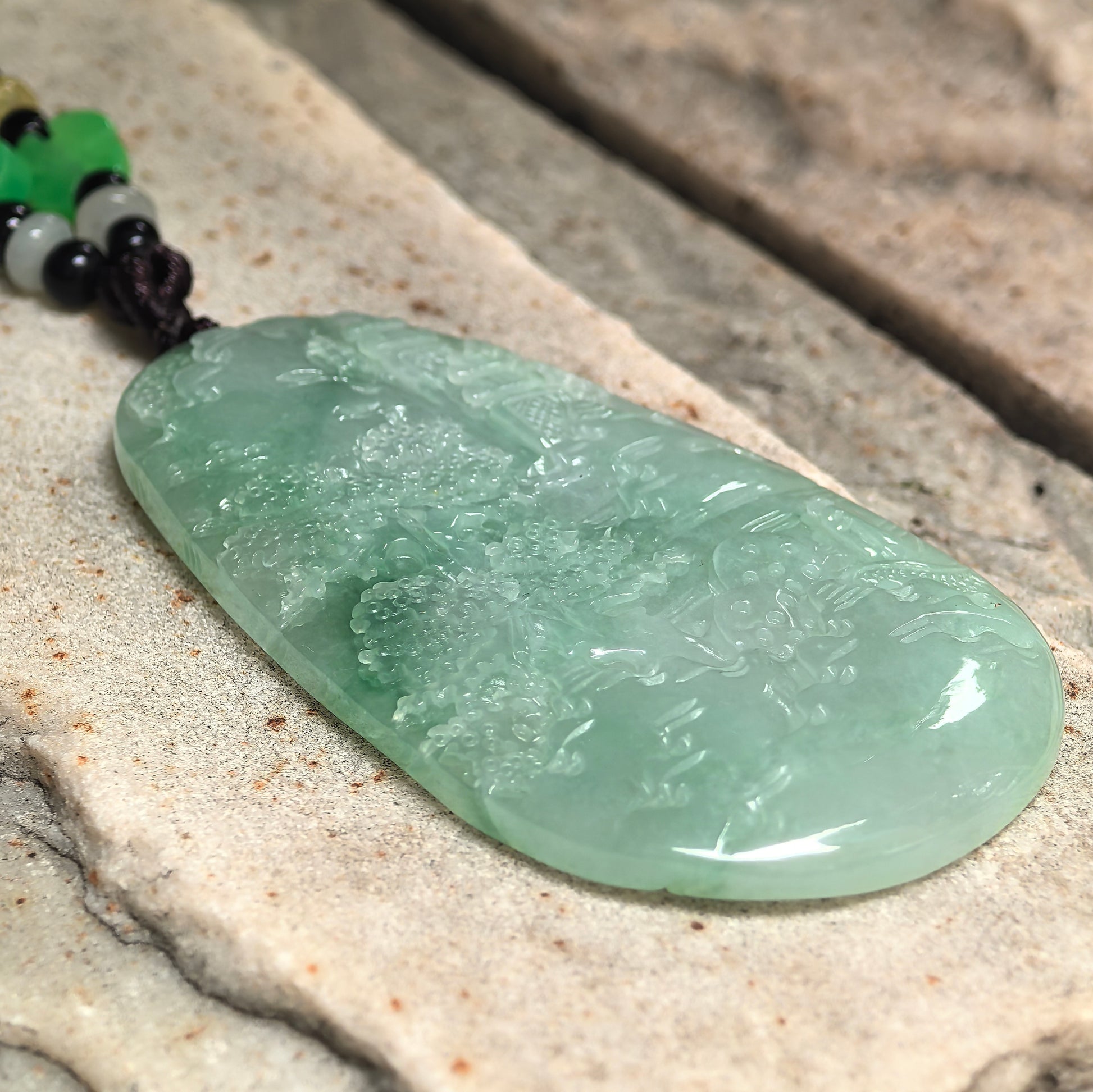 Large plaque-like green jadeite pendant with smooth luster and vivid color.
