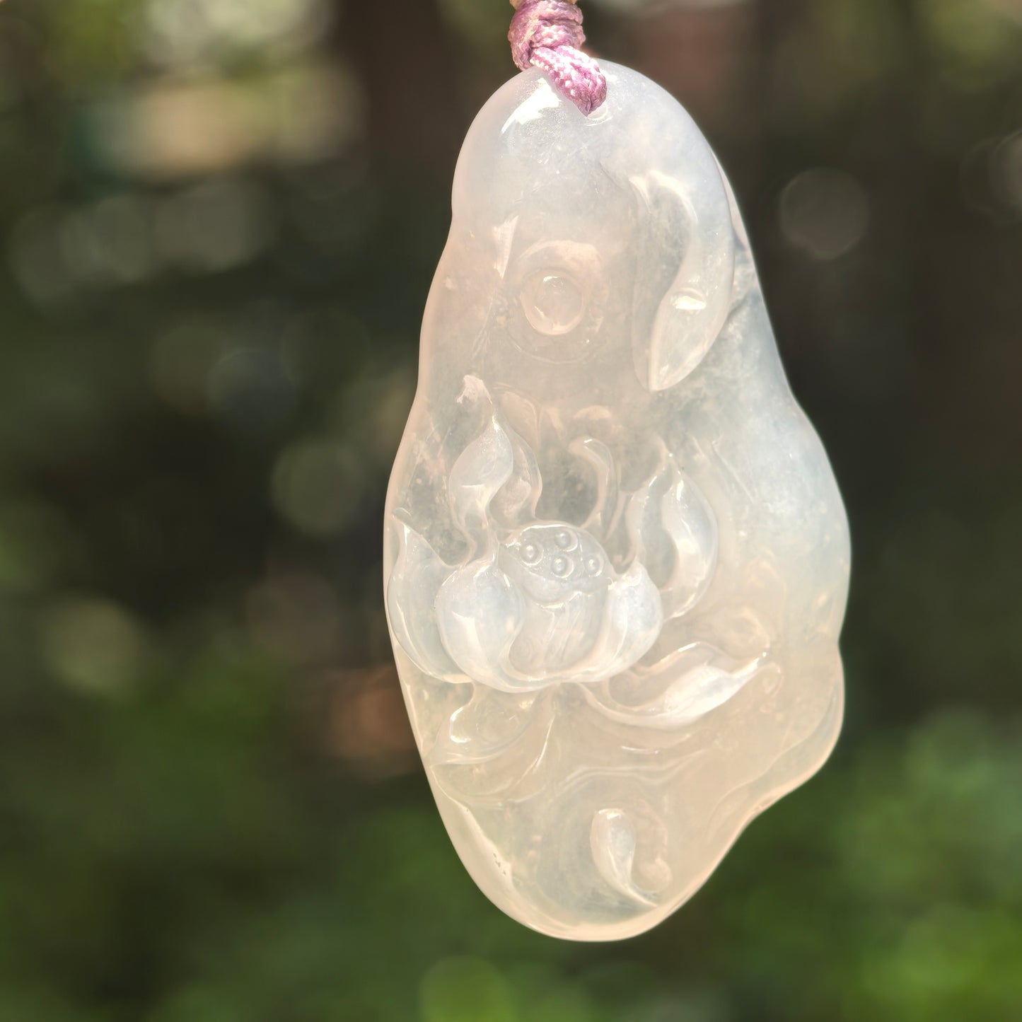 Natural Grade-A icy glutinous white lotus jadeite pendant hanging on cord in natural light.
