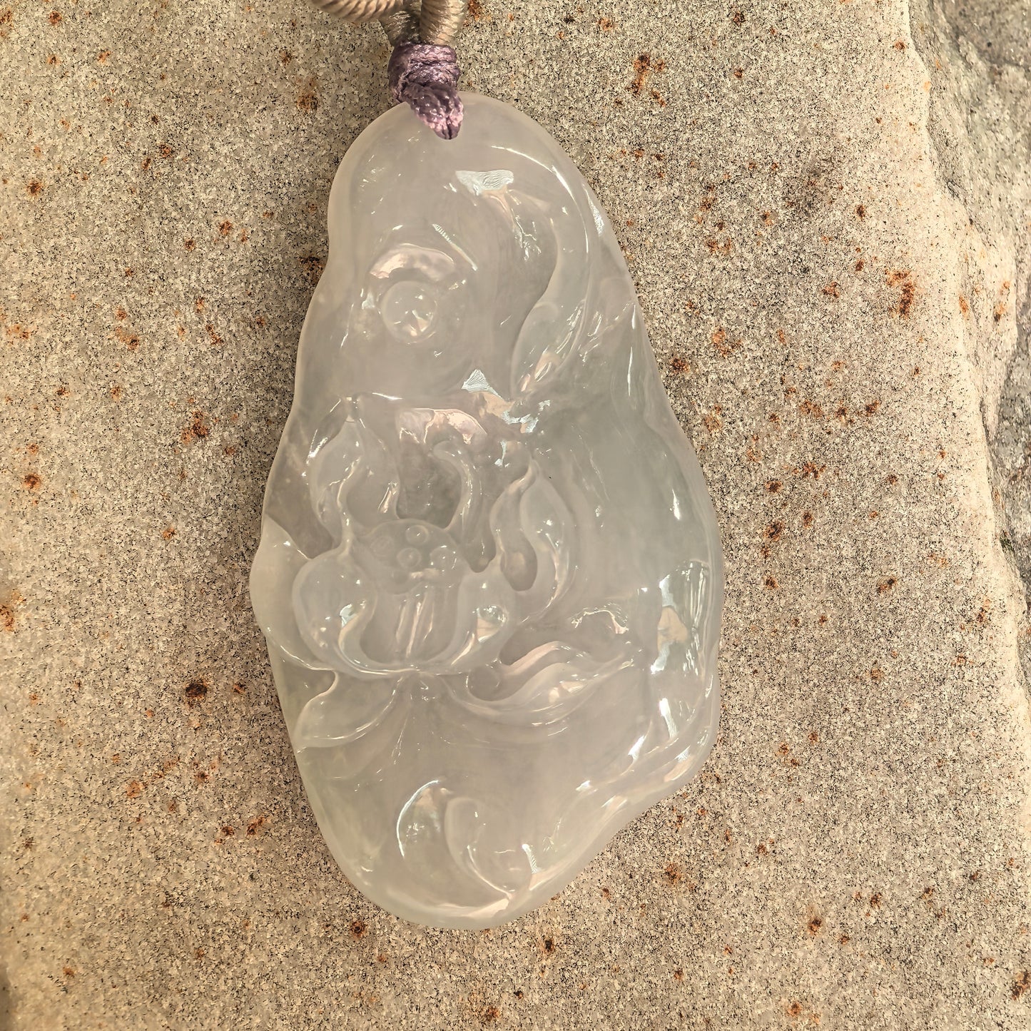 Close-up of a soft white jadeite lotus pendant showing smooth luster and gentle translucency.

