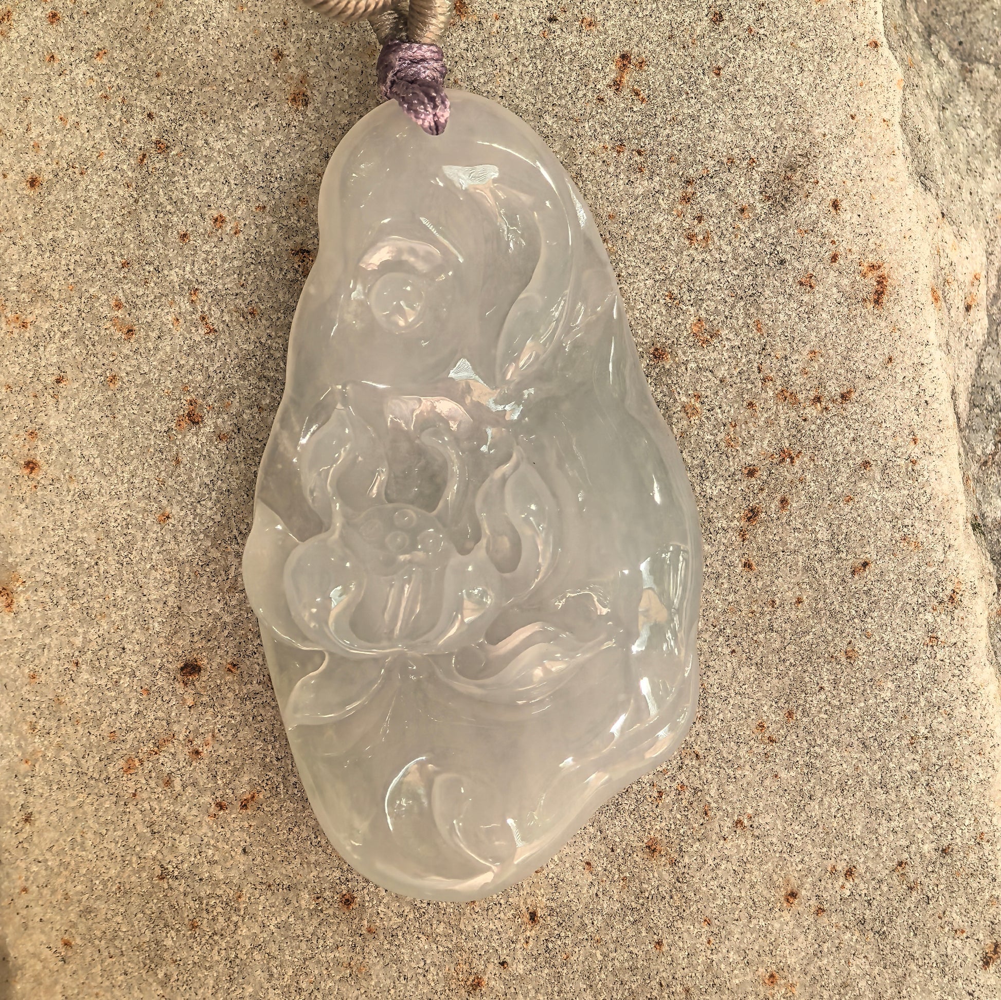 Close-up of a soft white jadeite lotus pendant showing smooth luster and gentle translucency.
