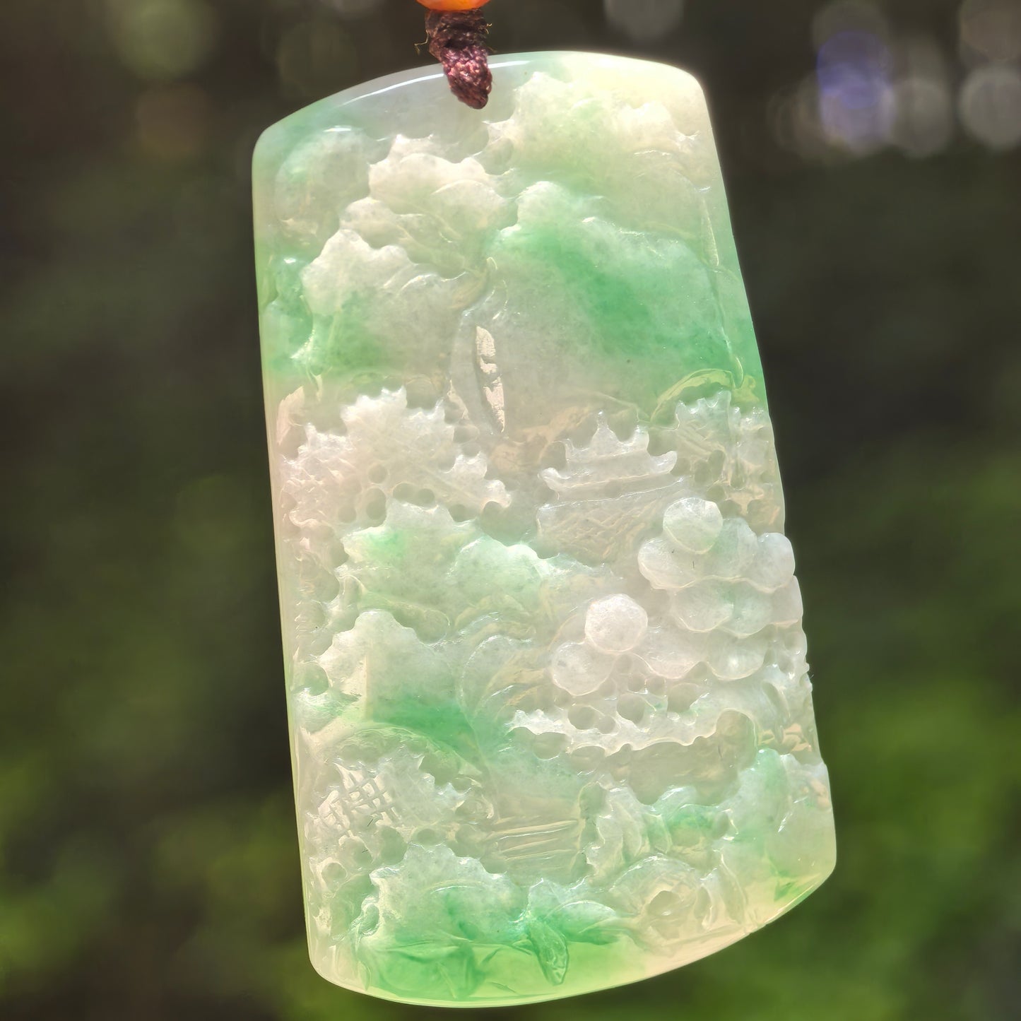 Natural Grade-A glutinous green landscape jadeite pendant in natural light.
