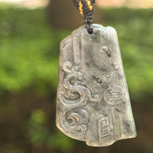Natural Grade-A glutinous gray-black antique phoenix jadeite pendant hanging on cord in natural light.
