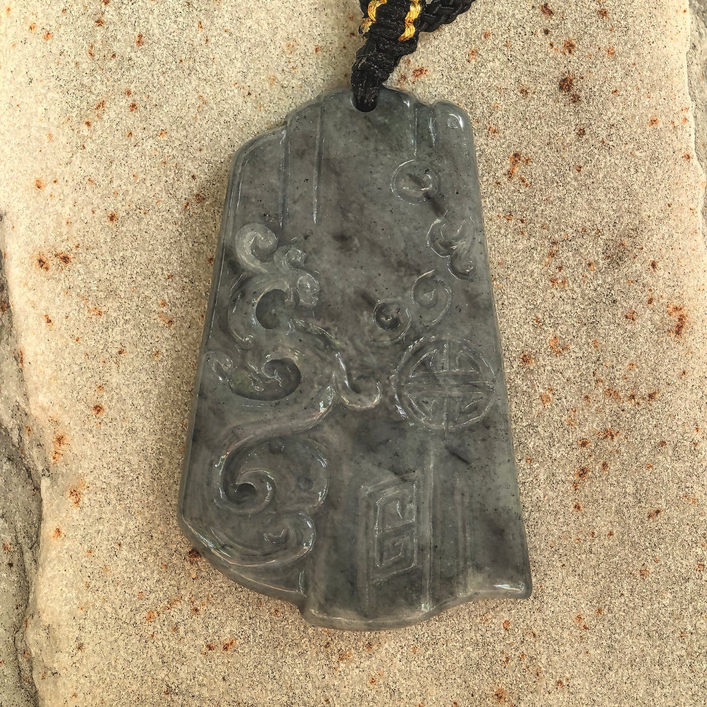 Close-up of antique-style jadeite pendant with phoenix, cloud motifs, and traditional patterns.
