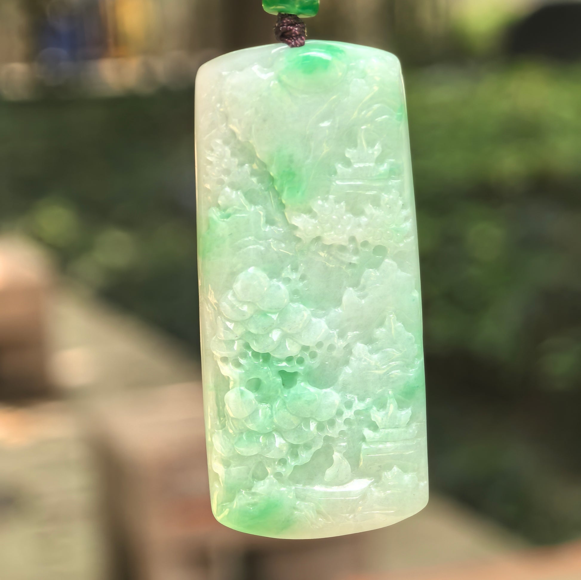 Natural Grade-A glutinous bright green landscape jadeite pendant in natural light.
