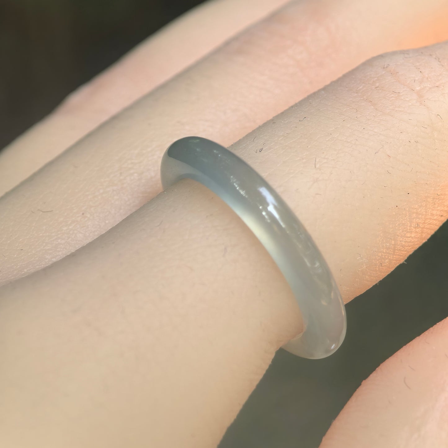 Natural Grade-A icy light green jadeite ring band worn on finger, showing slim rounded shape and soft translucency.
