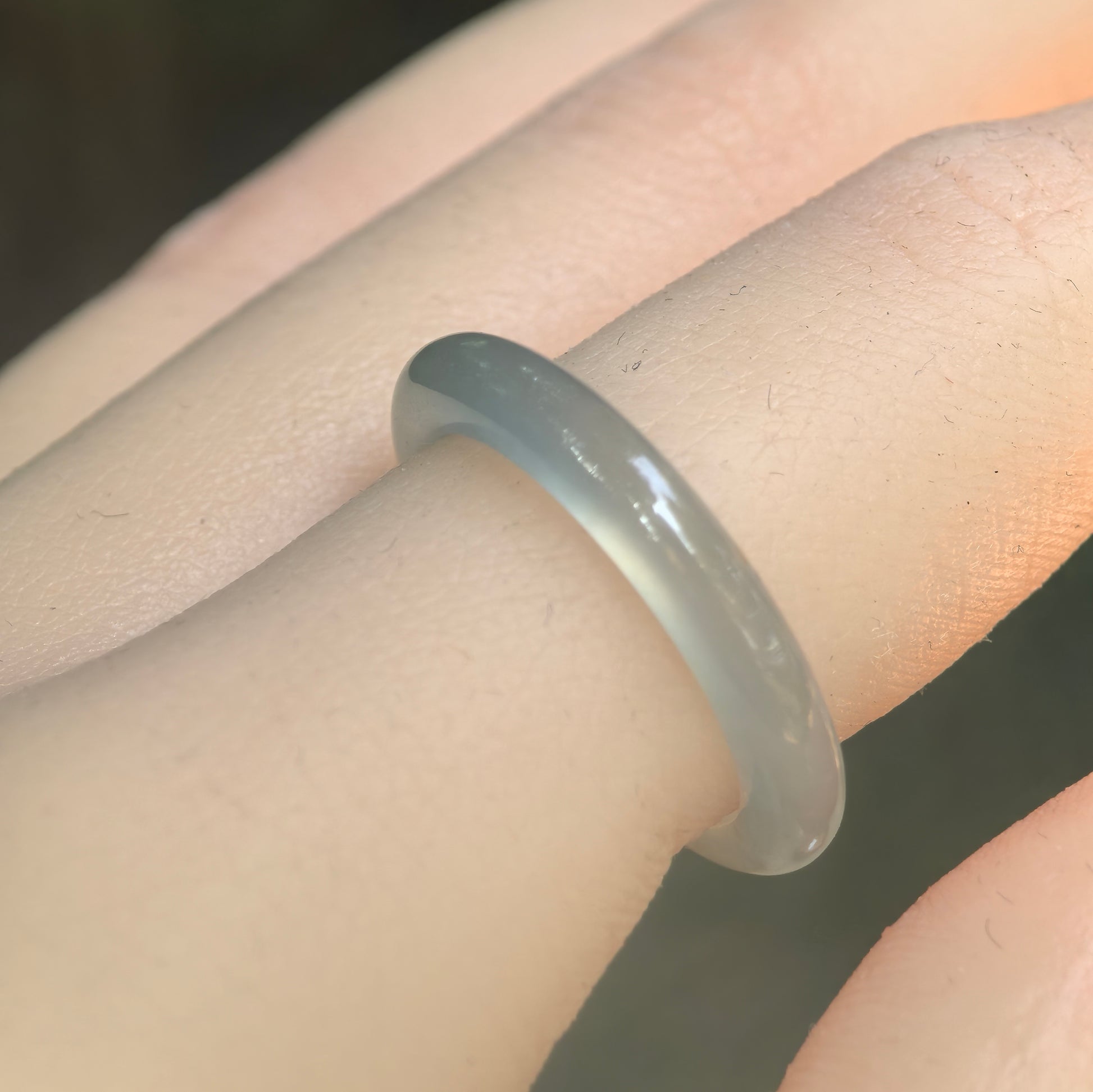 Natural Grade-A icy light green jadeite ring band worn on finger, showing slim rounded shape and soft translucency.
