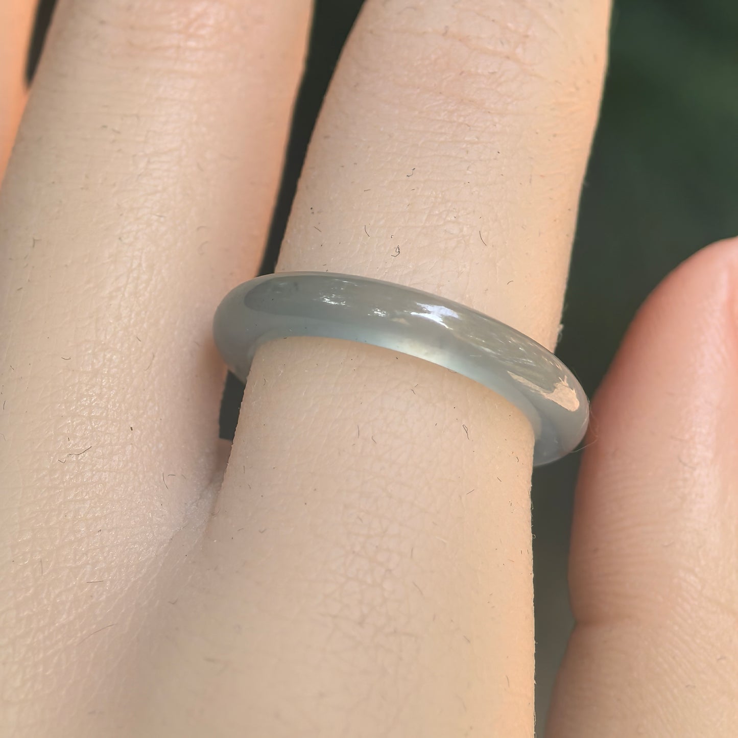 Close-up side view of light green jadeite ring band with smooth polished luster and bright reflective effect.
