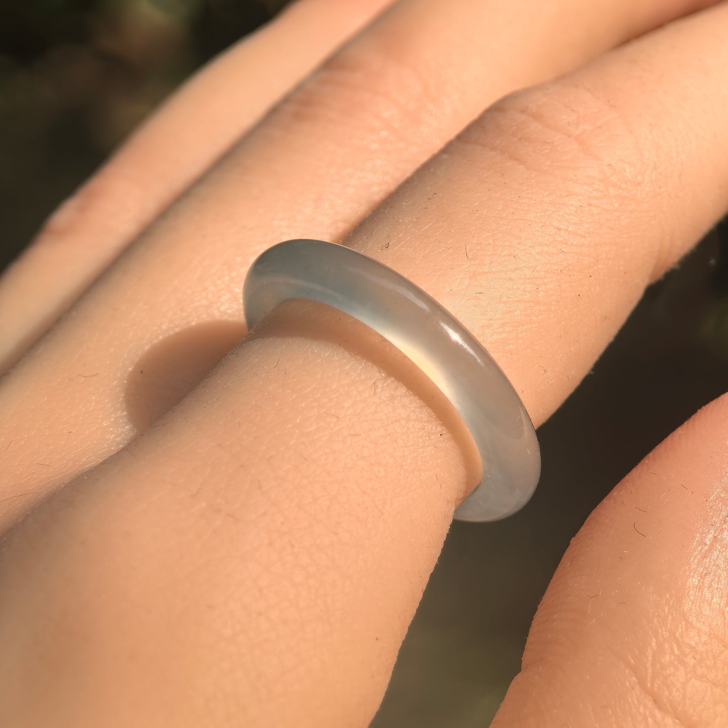 Natural Grade-A icy jadeite ring band worn under sunlight, showing clean light green color and rounded profile.
