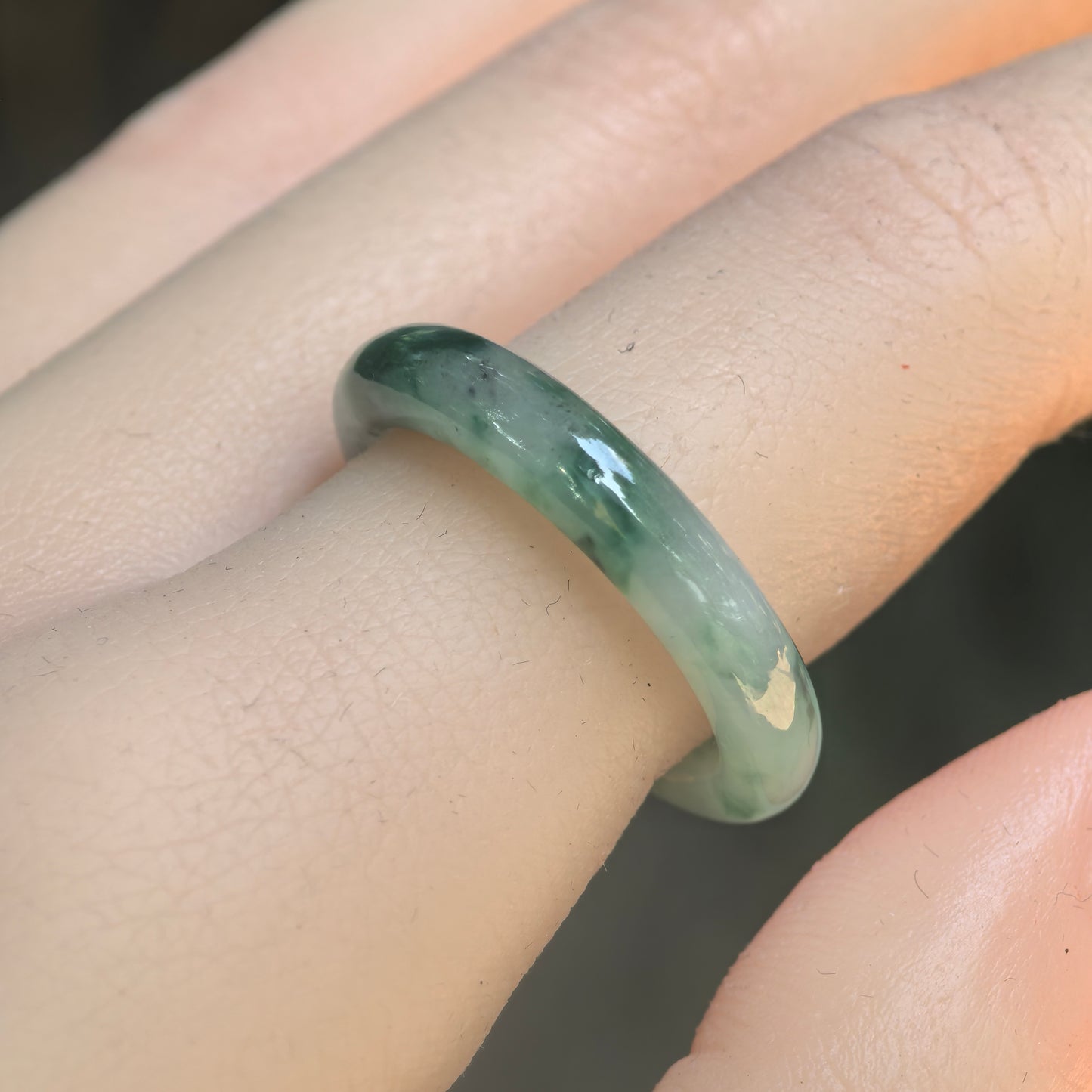 Natural Grade-A icy glutinous green floating flower jadeite ring band worn on finger under natural light.
