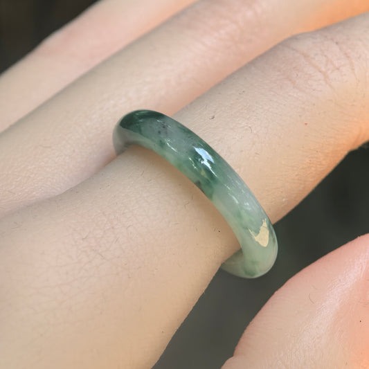 Natural Grade-A icy glutinous green floating flower jadeite ring band worn on finger under natural light.
