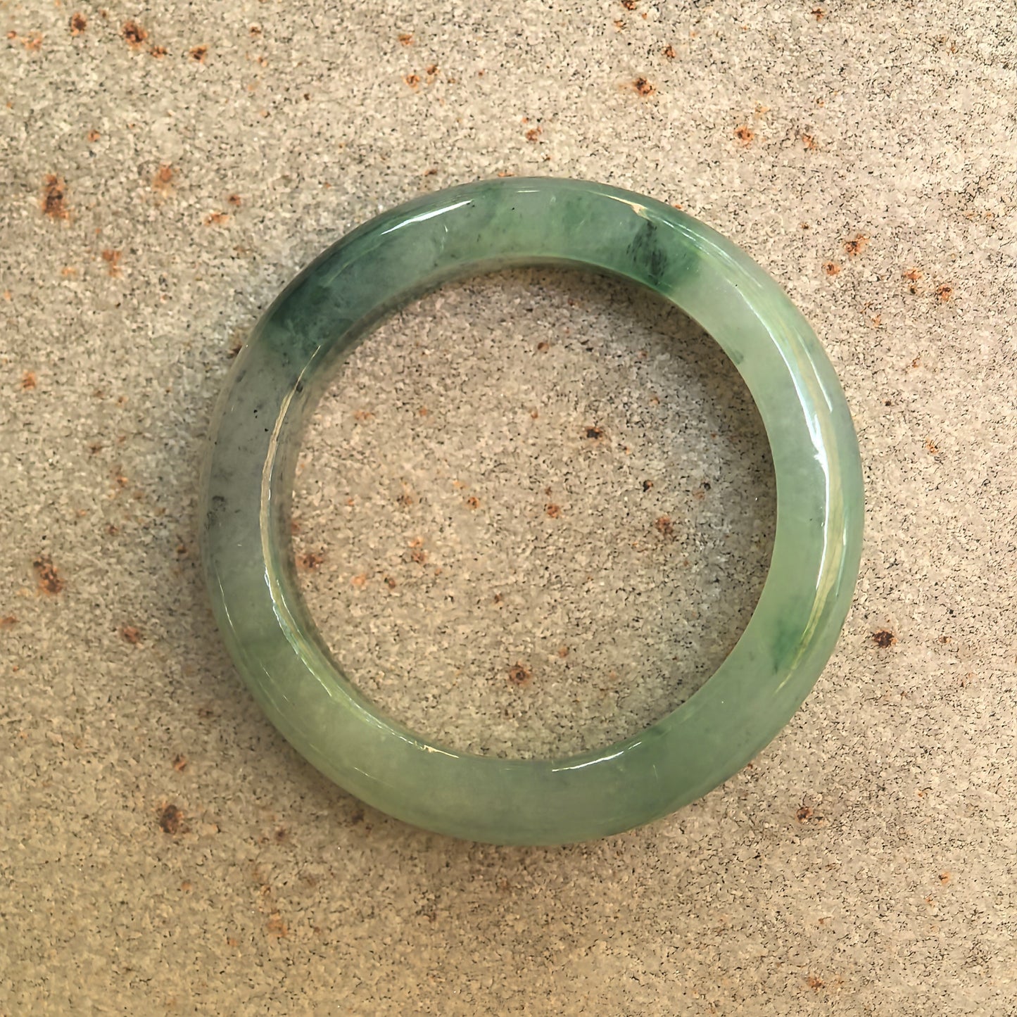 Top view of natural Grade-A green floating flower jadeite ring band showing circular shape and translucency.
