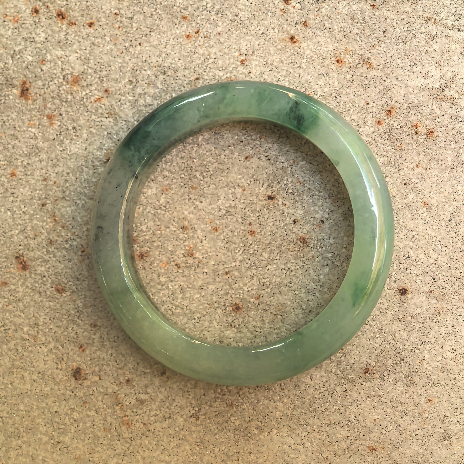 Top view of natural Grade-A green floating flower jadeite ring band showing circular shape and translucency.
