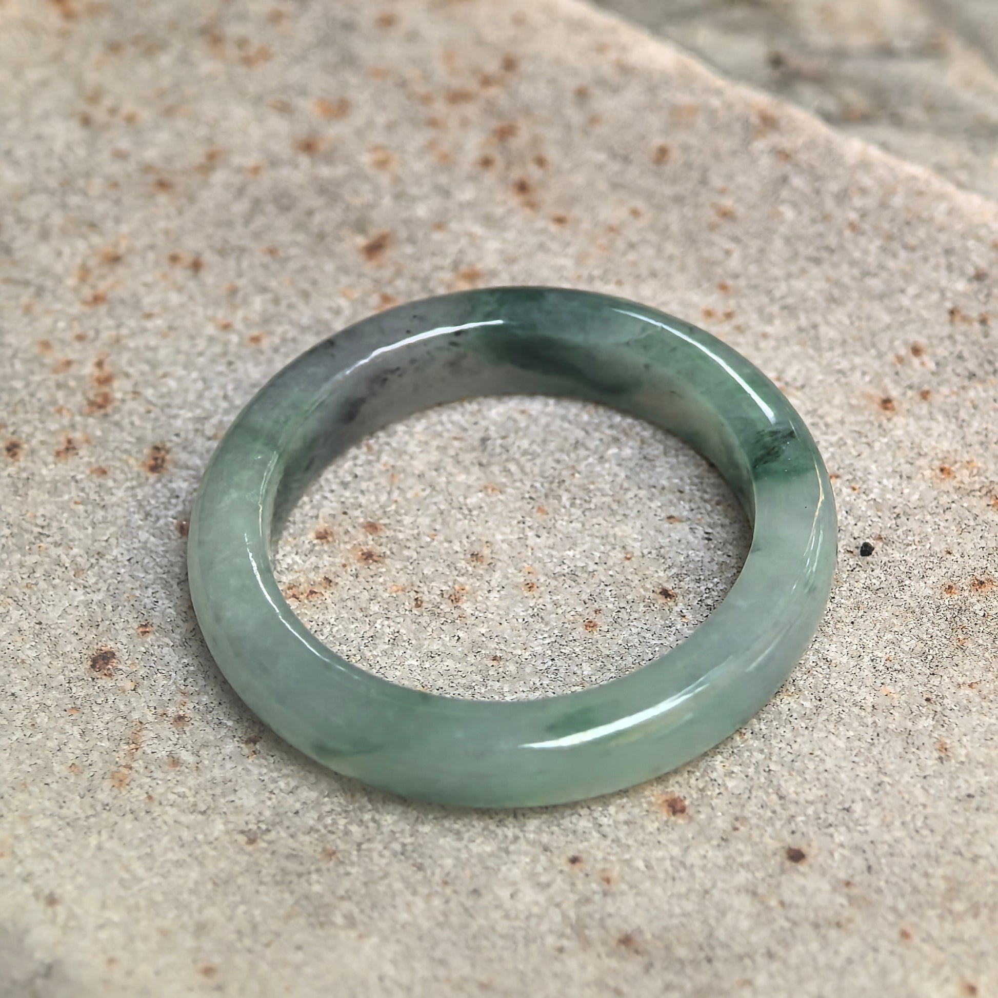 Side view of icy glutinous green jadeite ring band showing rounded profile and natural jadeite texture.
