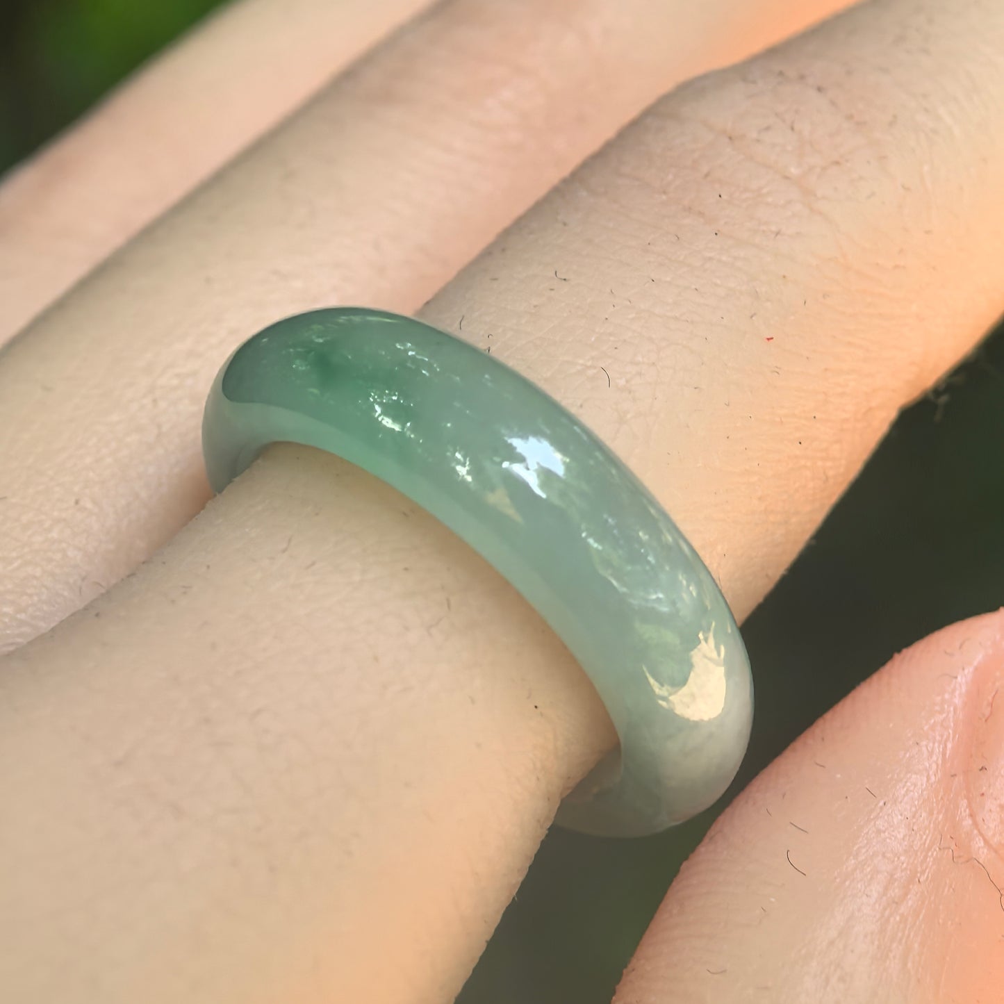 Natural Grade-A icy glutinous light green jadeite ring band worn on finger, showing smooth rounded profile and soft jadeite luster.
