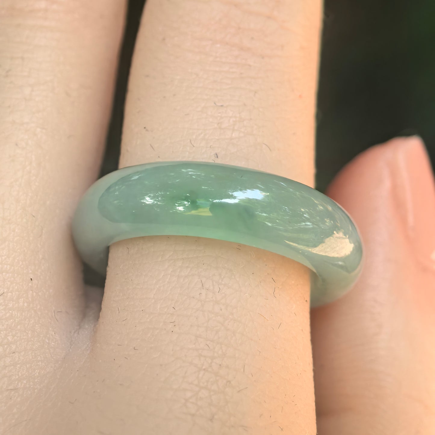 Close-up of light green jadeite ring band showing good translucency, polished surface, and visible natural cottony texture.
