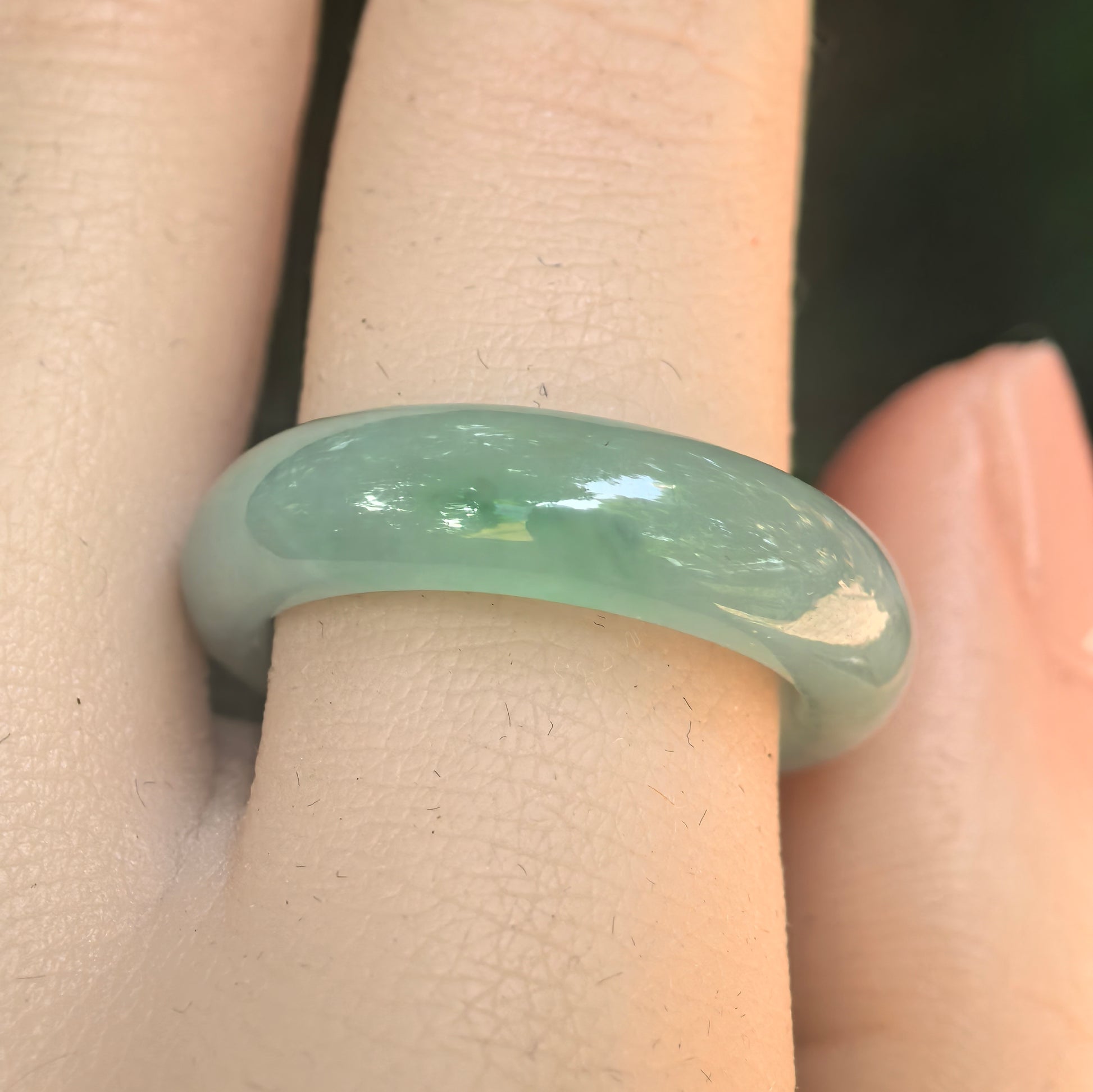 Close-up of light green jadeite ring band showing good translucency, polished surface, and visible natural cottony texture.
