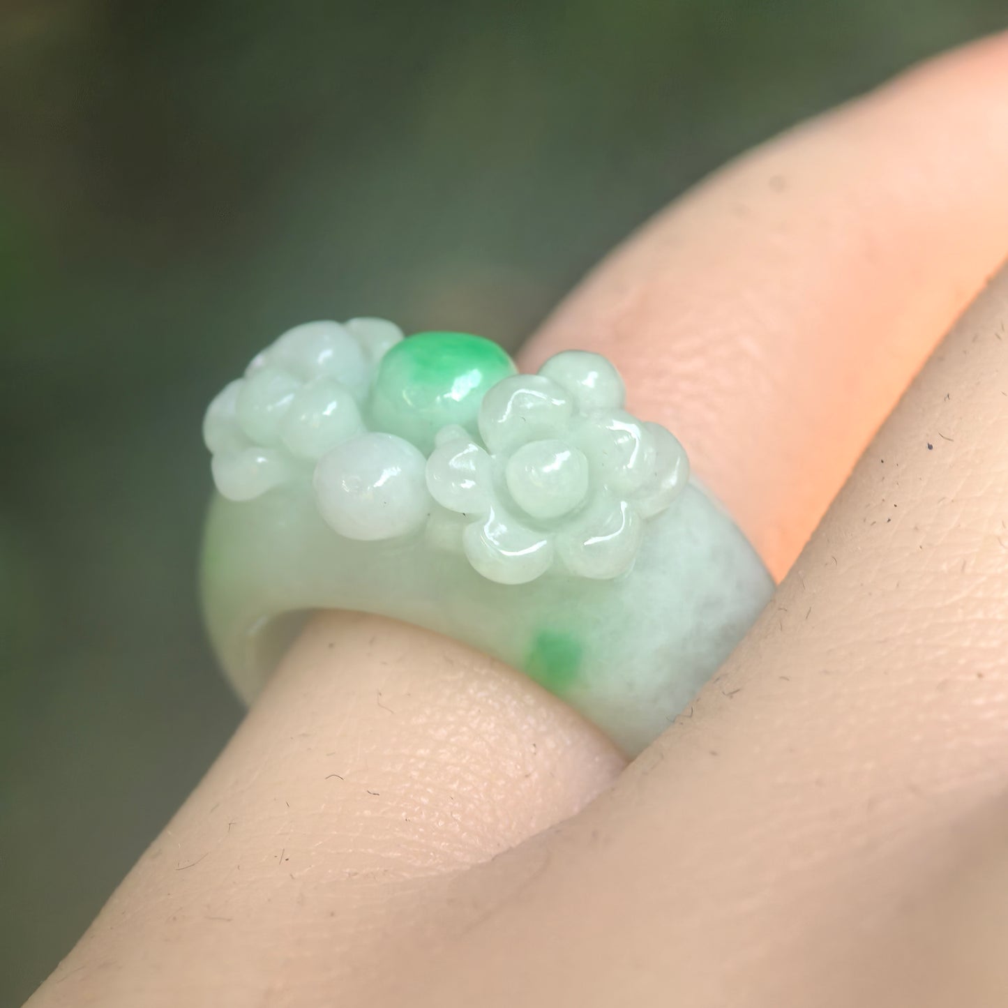 Natural Grade-A glutinous light green floral jadeite ring band worn on finger under natural light.
