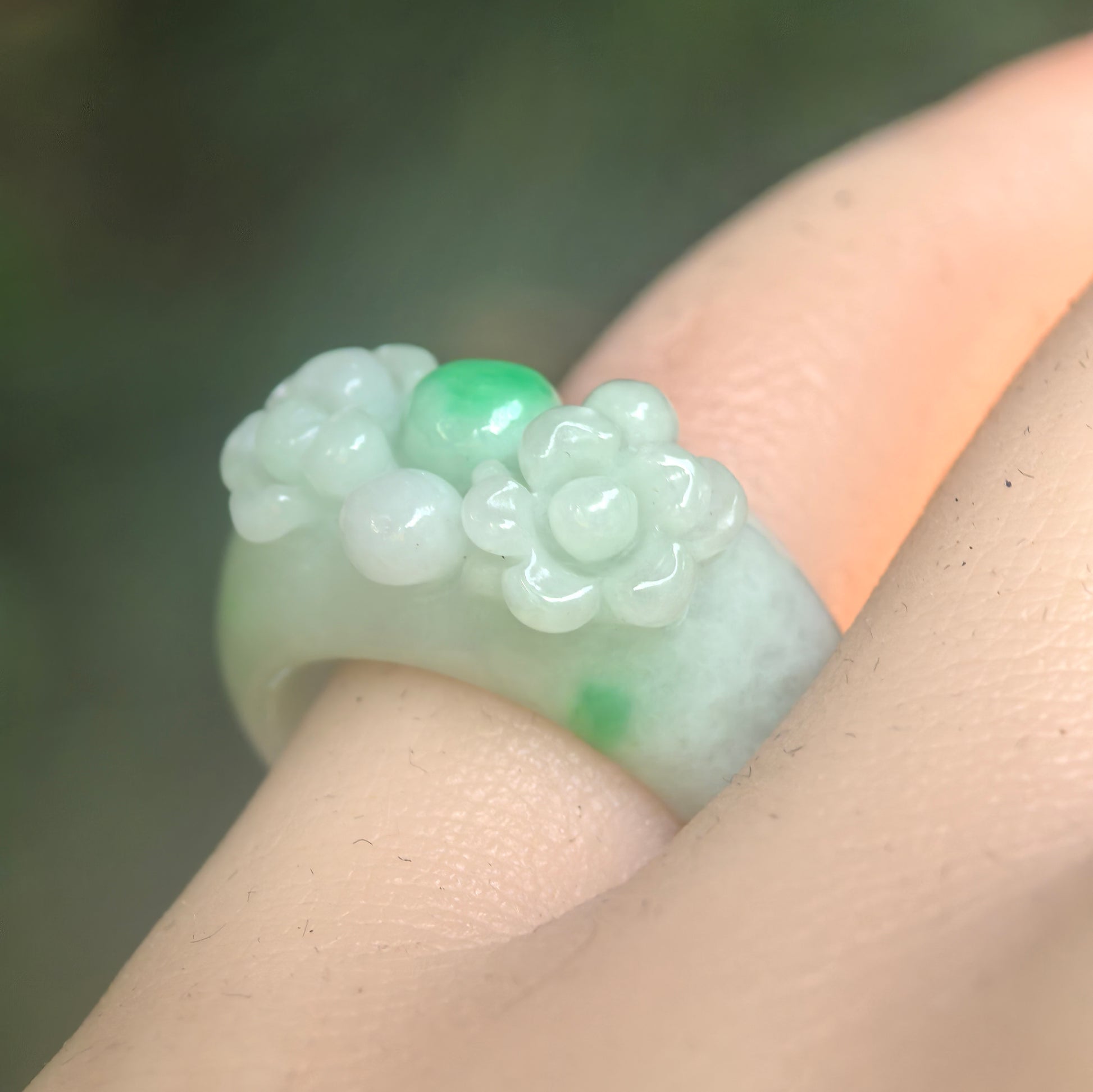Natural Grade-A glutinous light green floral jadeite ring band worn on finger under natural light.
