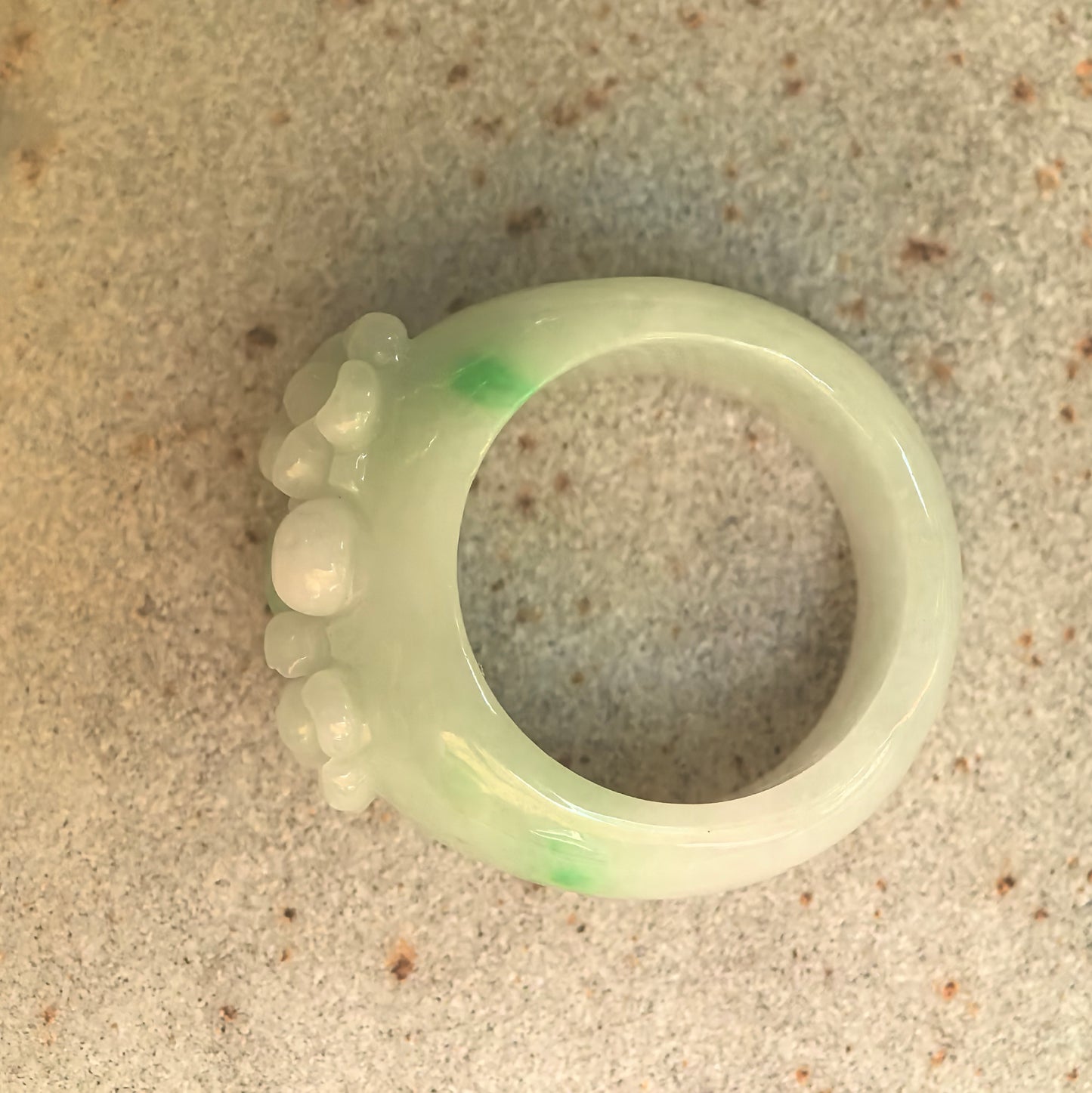 Top view of floral carved jadeite ring band with soft light green body and brighter green accents.
