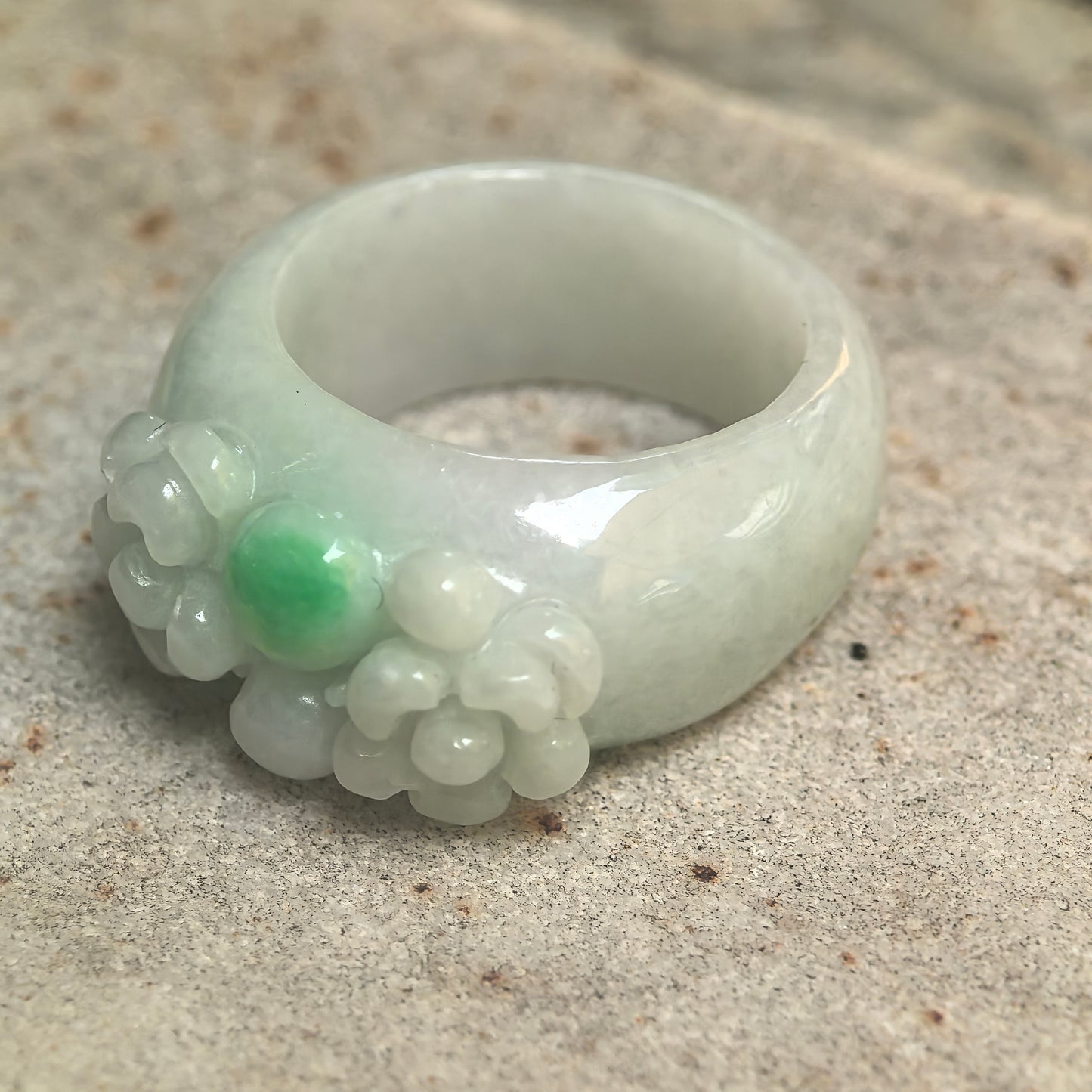 Side view of glutinous jadeite ring band showing rounded structure and carved flower detail.

