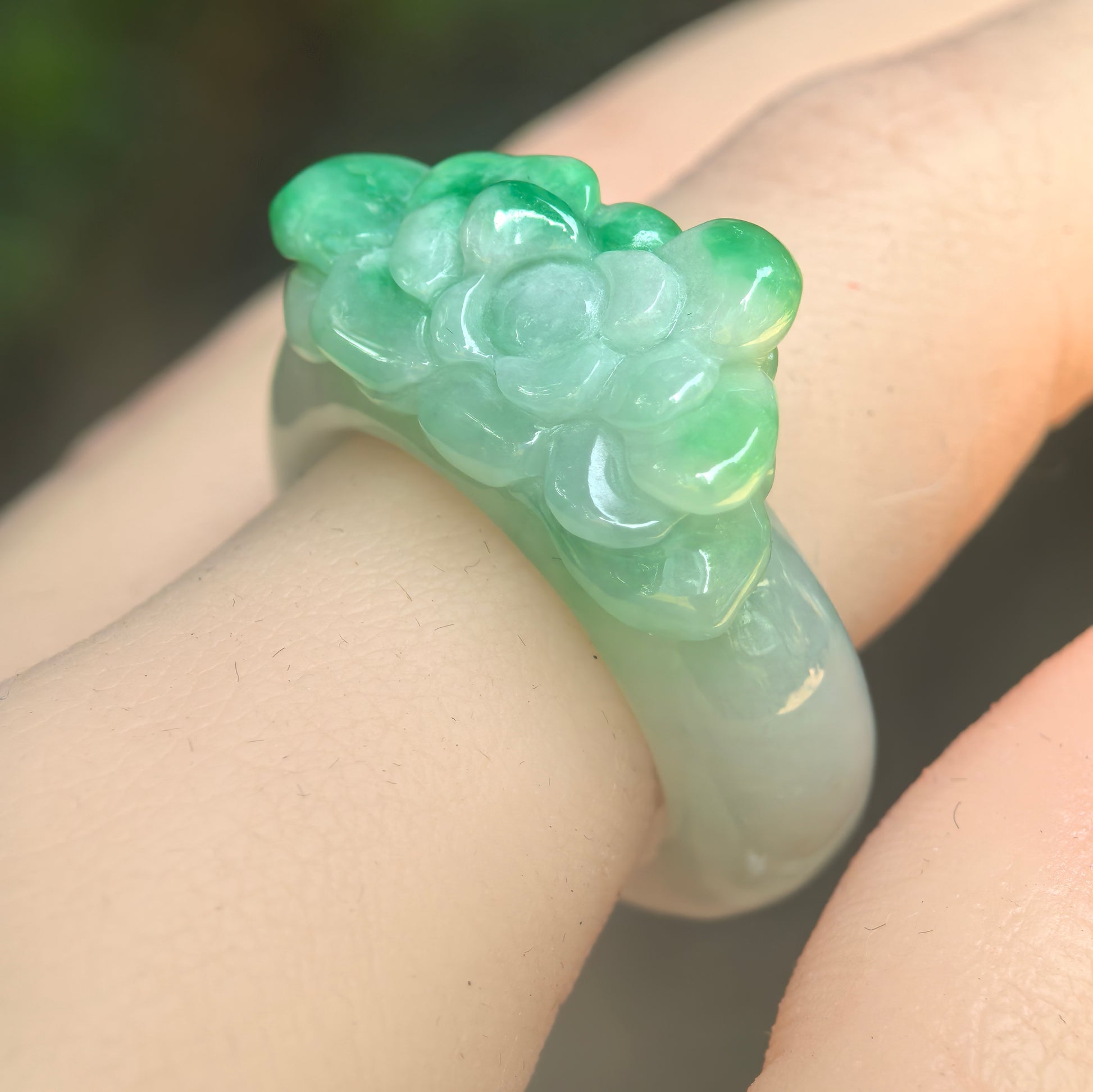 Natural Grade-A glutinous green floral jadeite ring band worn on finger under natural light.
