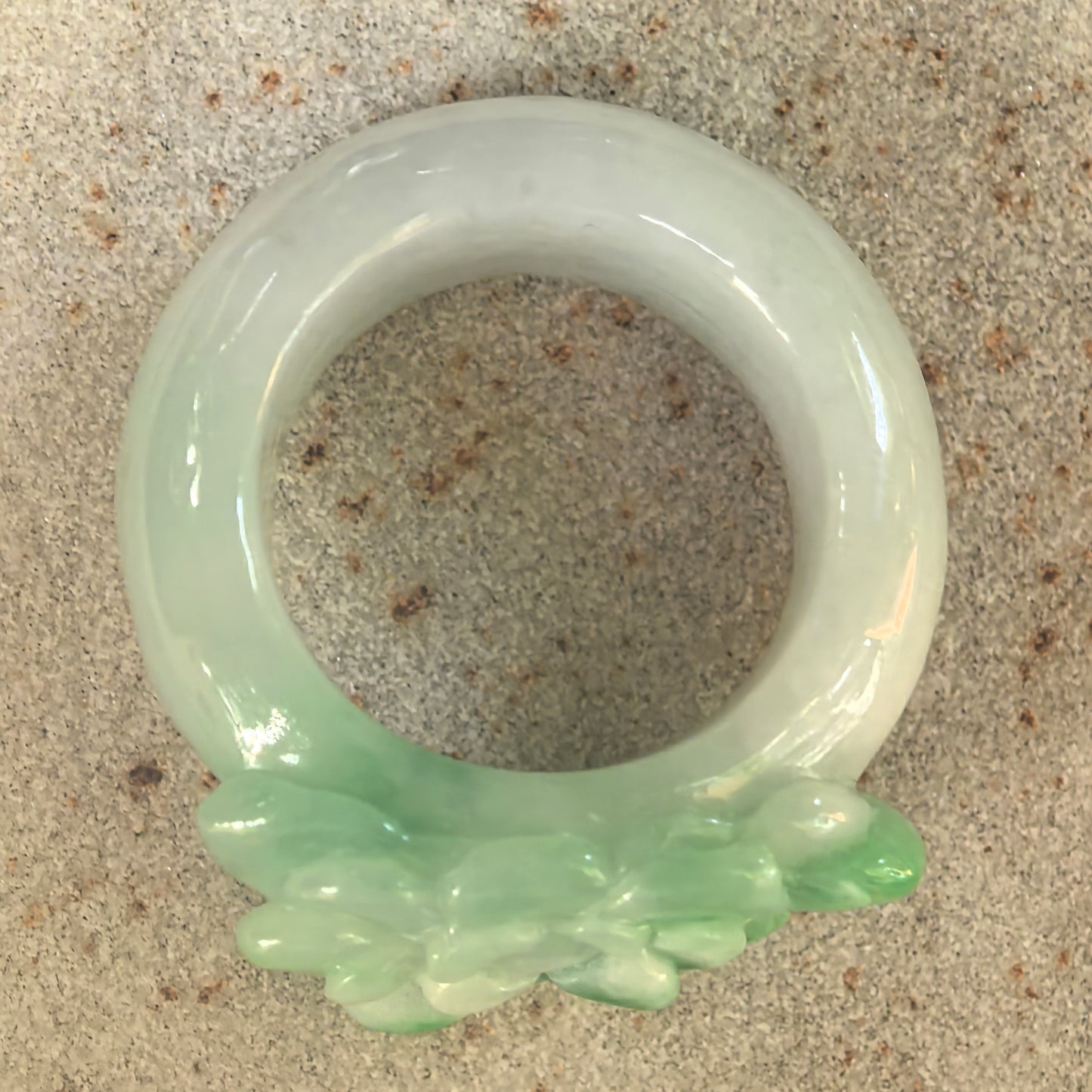 Top view of light green jadeite ring band with brighter green flower carving on the front.
