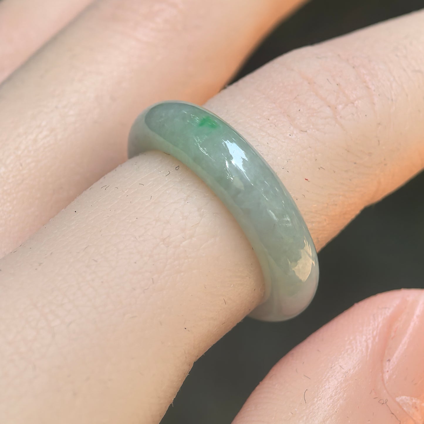 Natural Grade-A glutinous pale green jadeite ring band worn on finger under natural light.
