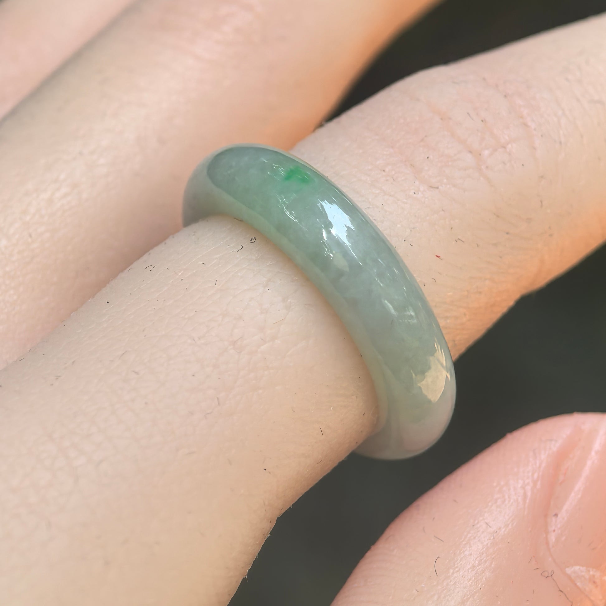 Natural Grade-A glutinous pale green jadeite ring band worn on finger under natural light.

