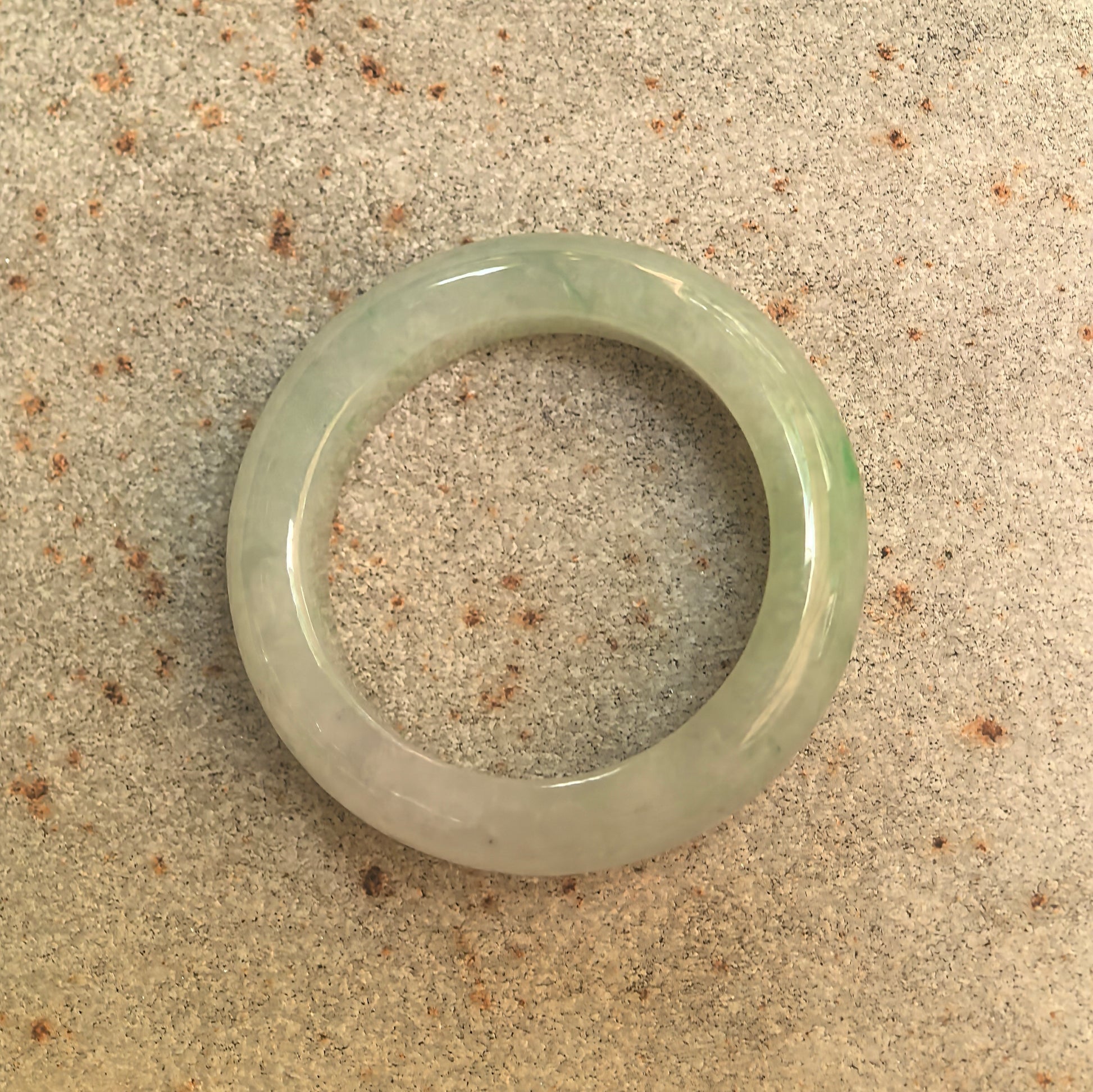 Top view of glutinous pale green jadeite ring band showing rounded full-circle profile.
