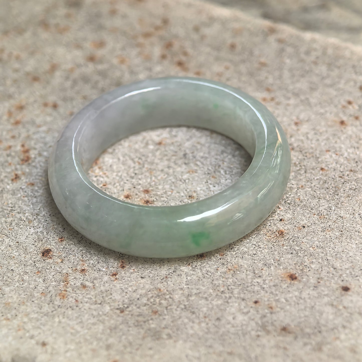 Side view of natural jadeite ring band showing smooth polished thickness and soft translucency.