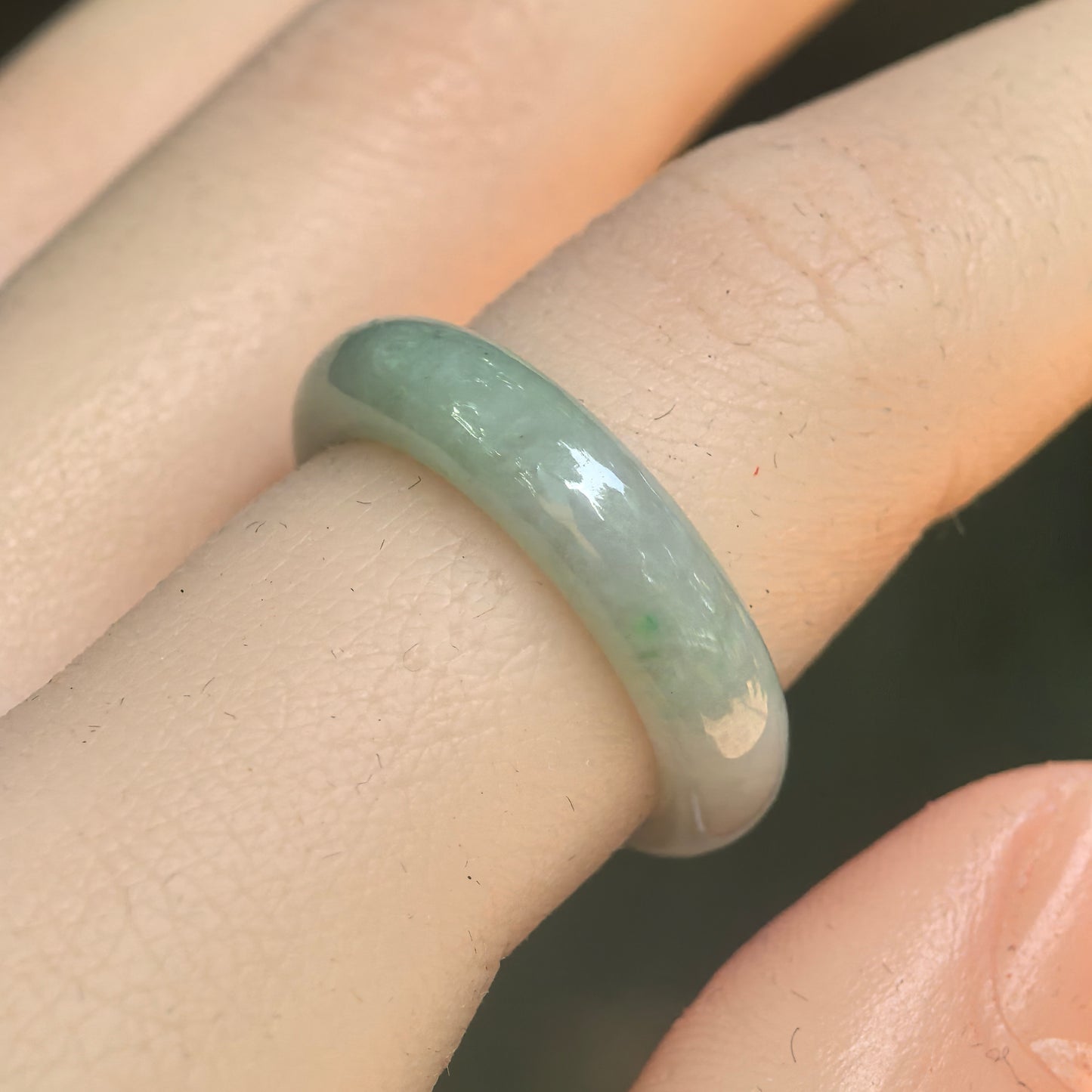 Natural Grade-A glutinous light green jadeite ring band worn on finger under natural light.
