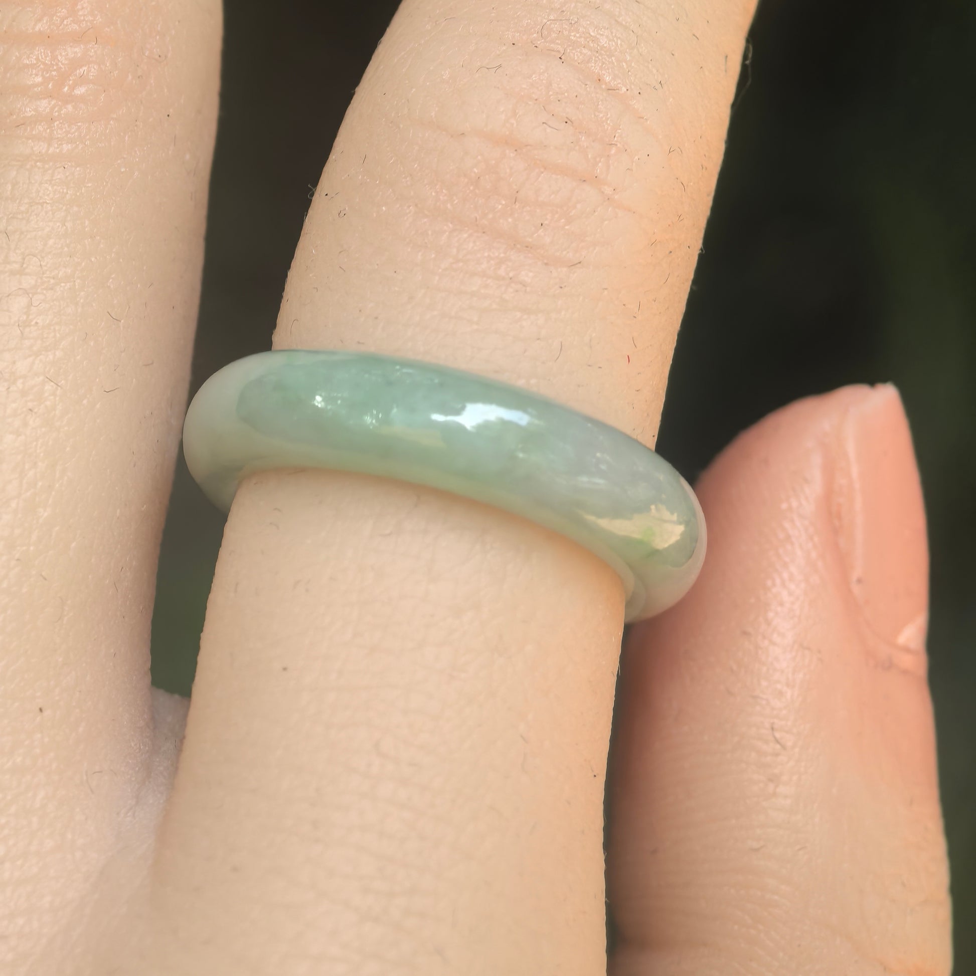 Close-up of light green jadeite ring band showing soft translucency and smooth polish.
