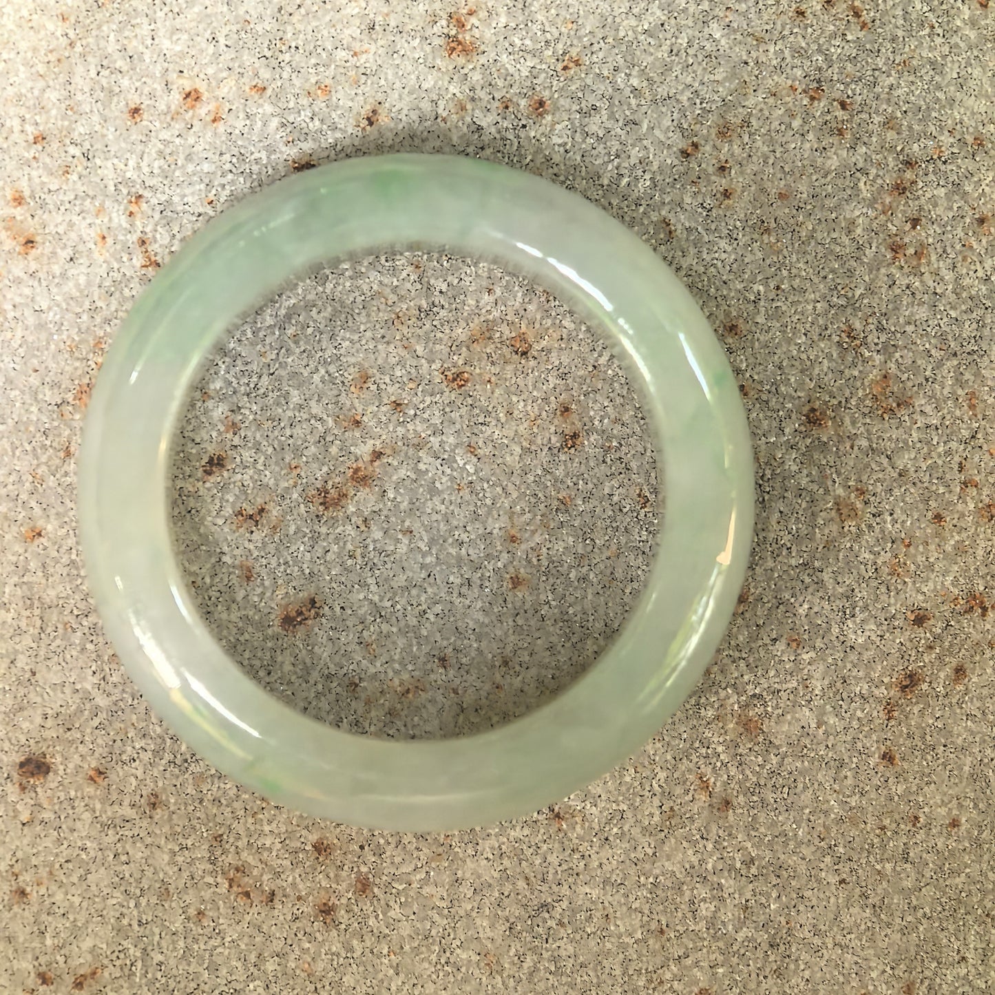 Top view of glutinous light green jadeite ring band showing rounded circular profile.
