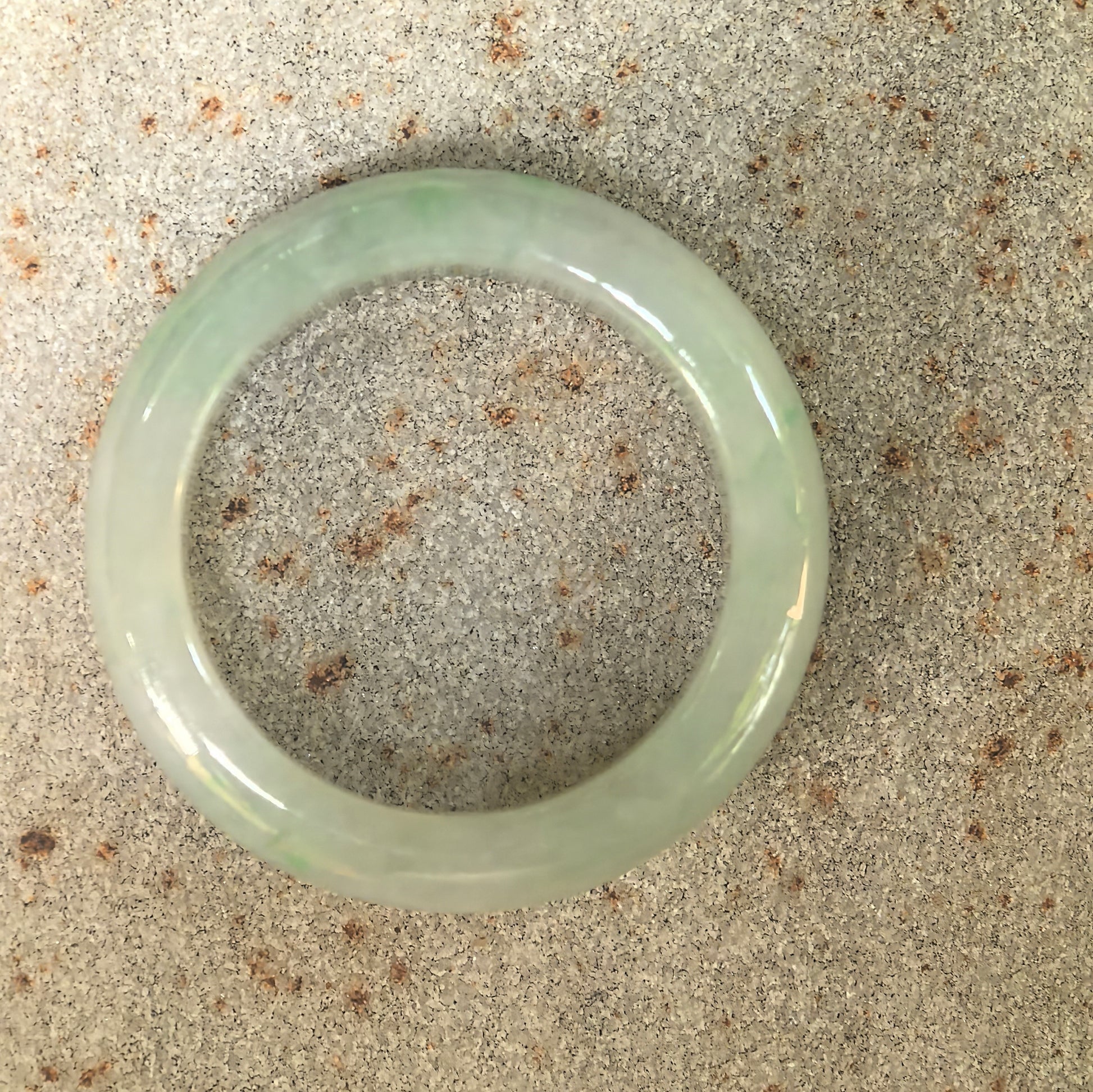 Top view of glutinous light green jadeite ring band showing rounded circular profile.

