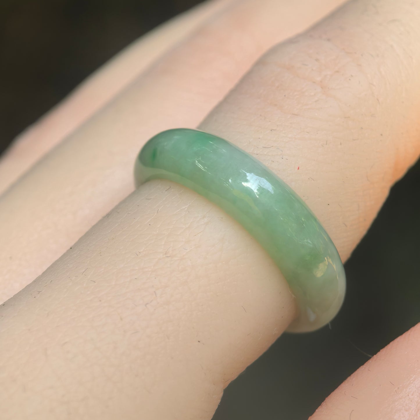 Natural Grade-A glutinous light green jadeite ring band worn on finger under natural light.
