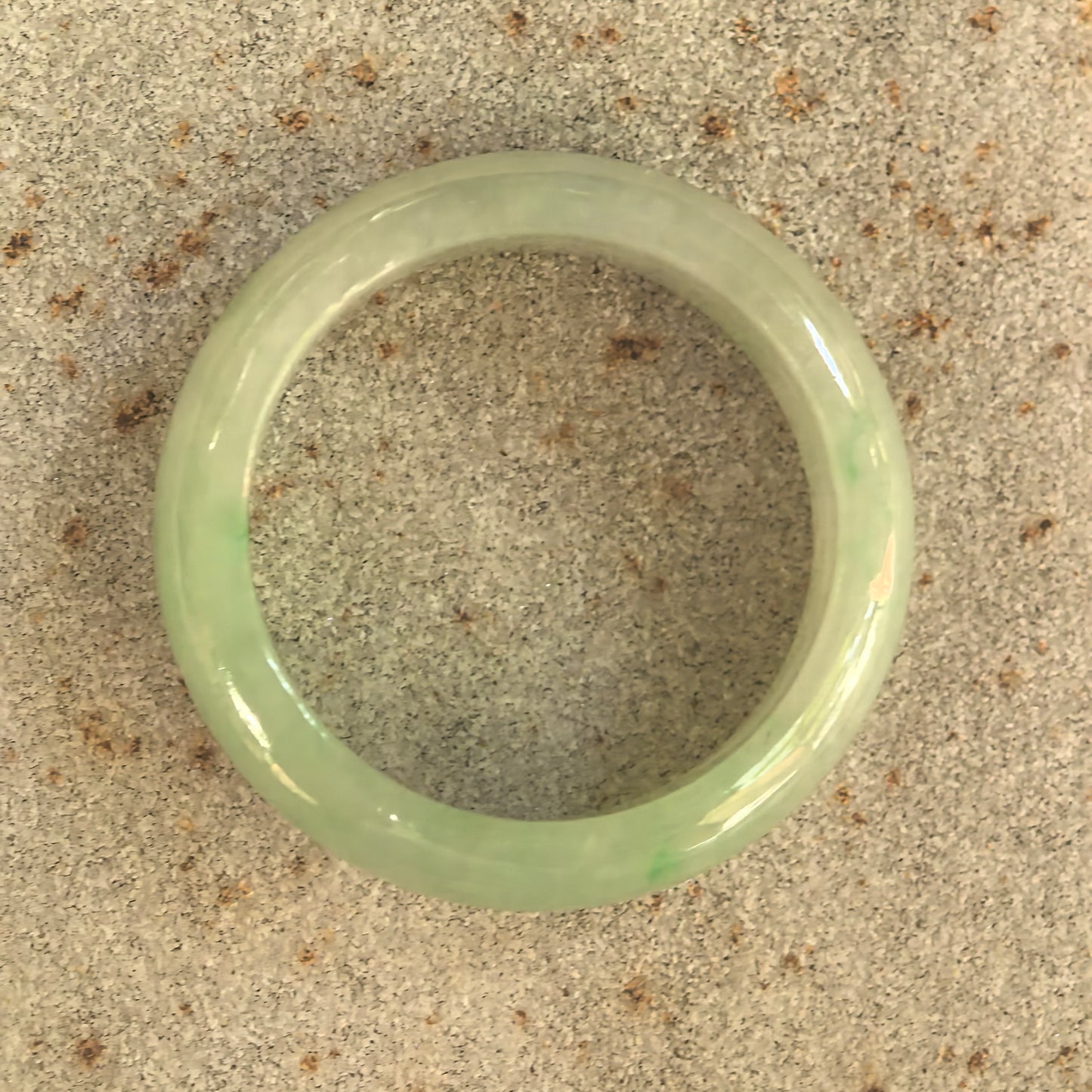 Top view of glutinous light green jadeite ring band showing rounded circular shape.
