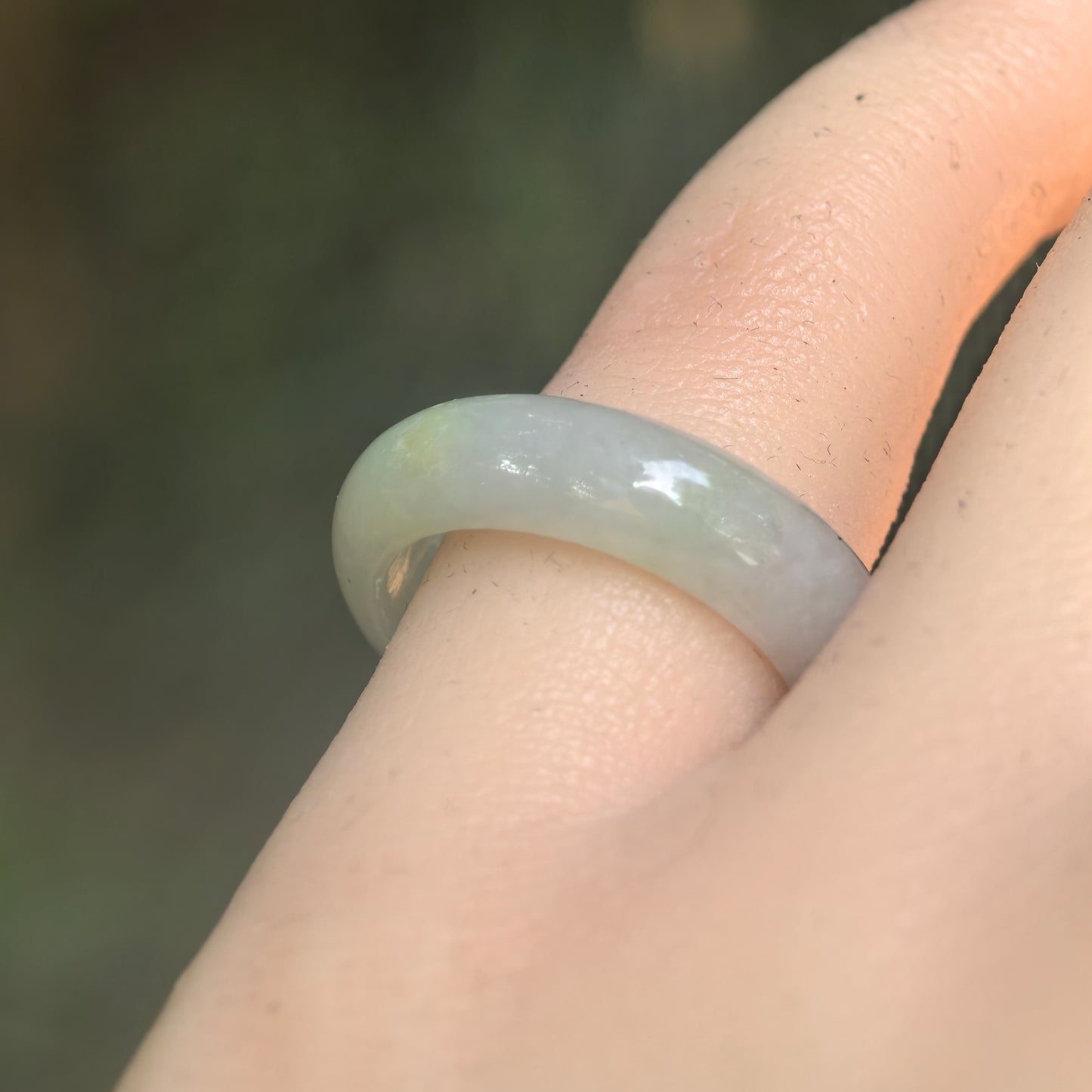 Natural Grade-A glutinous light green jadeite ring band worn on finger under natural light.
