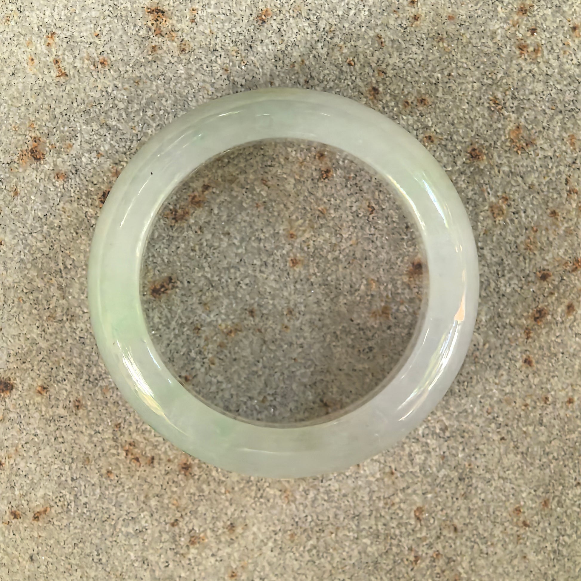 Top view of natural Grade-A glutinous light green jadeite ring band showing rounded circular shape.
