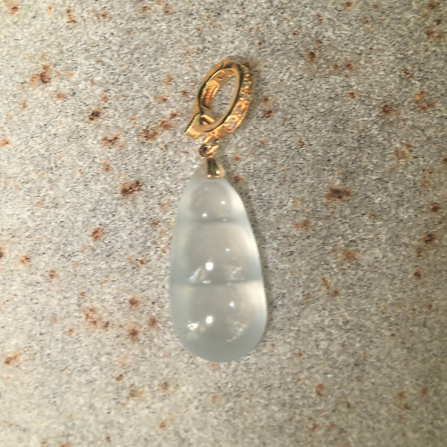 Close-up of icy white jadeite bean pendant with 18K gold and diamond-accent bail.
