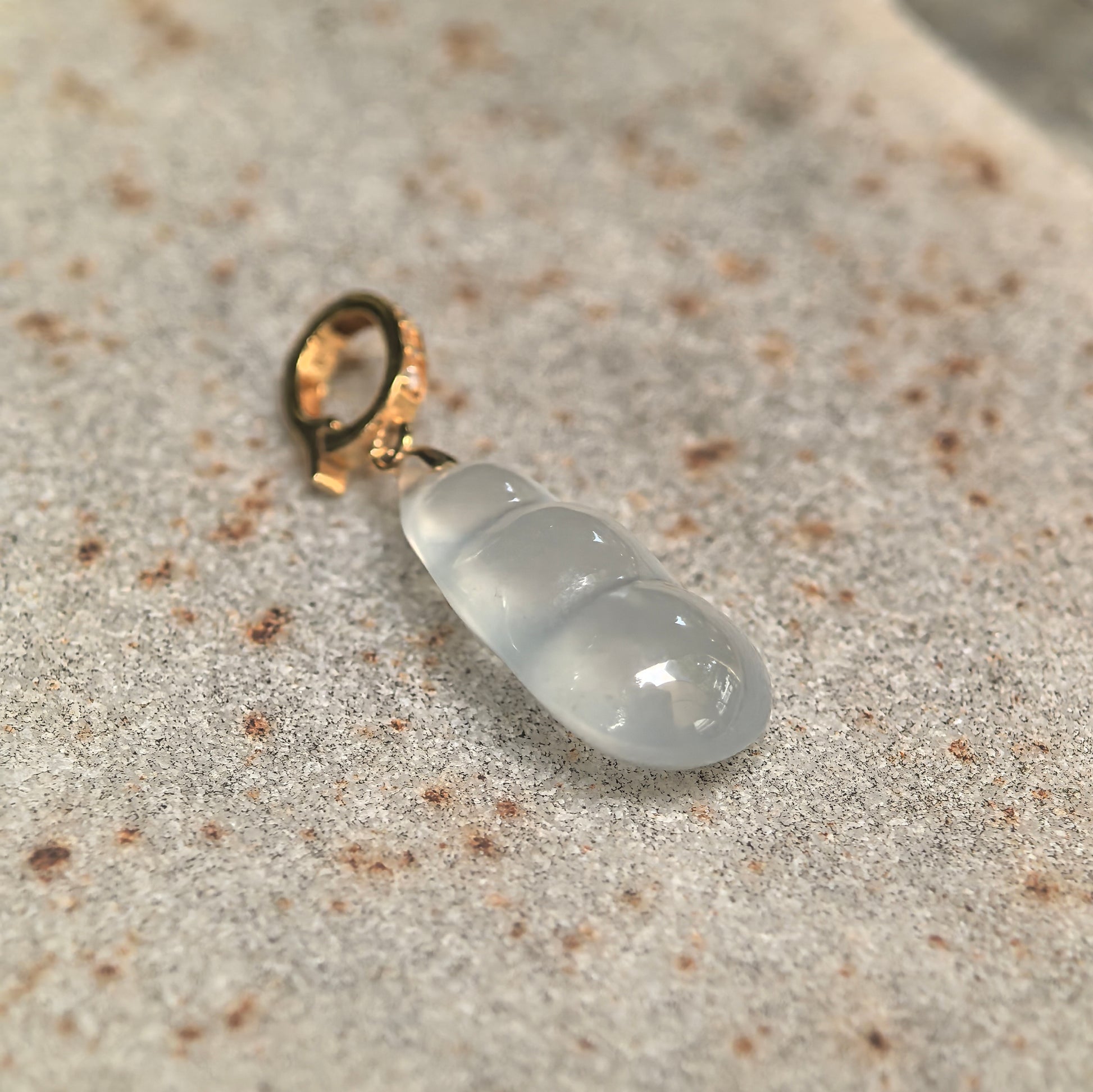 Natural Grade-A white jadeite bean pendant showing watery luster and soft translucency.
