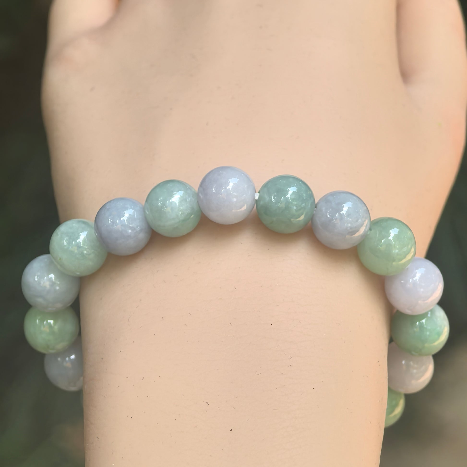 Close-up of green and pale lavender jadeite bracelet beads showing polished luster.
